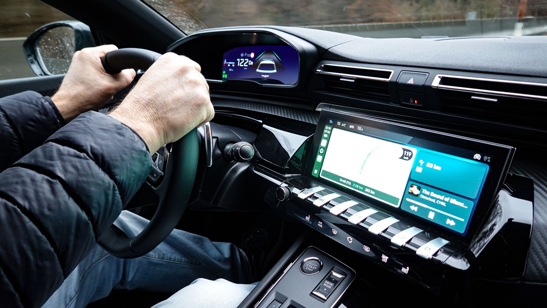 A detailed view of a car's interior with hands on the steering wheel, showcasing modern technology.