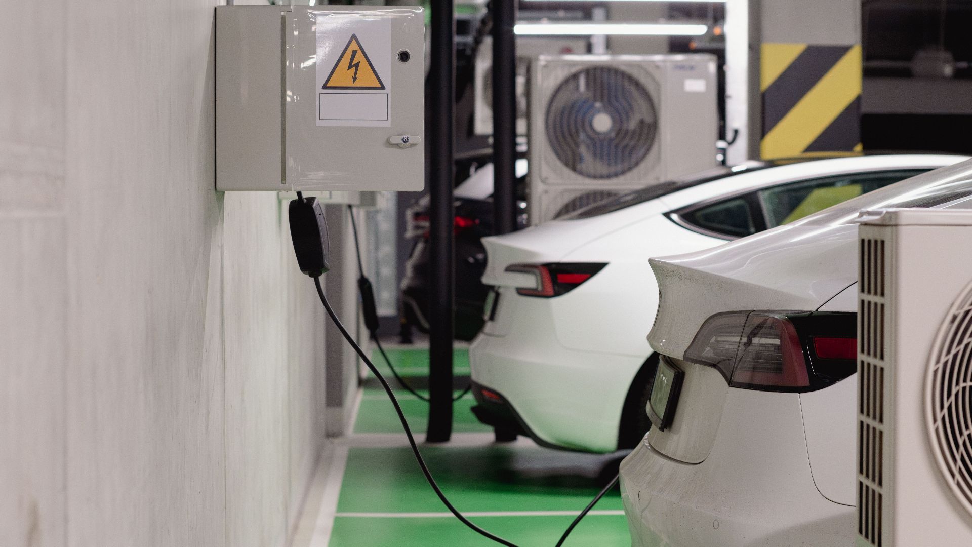 Electric vehicles charging at an indoor station in a modern underground garage.