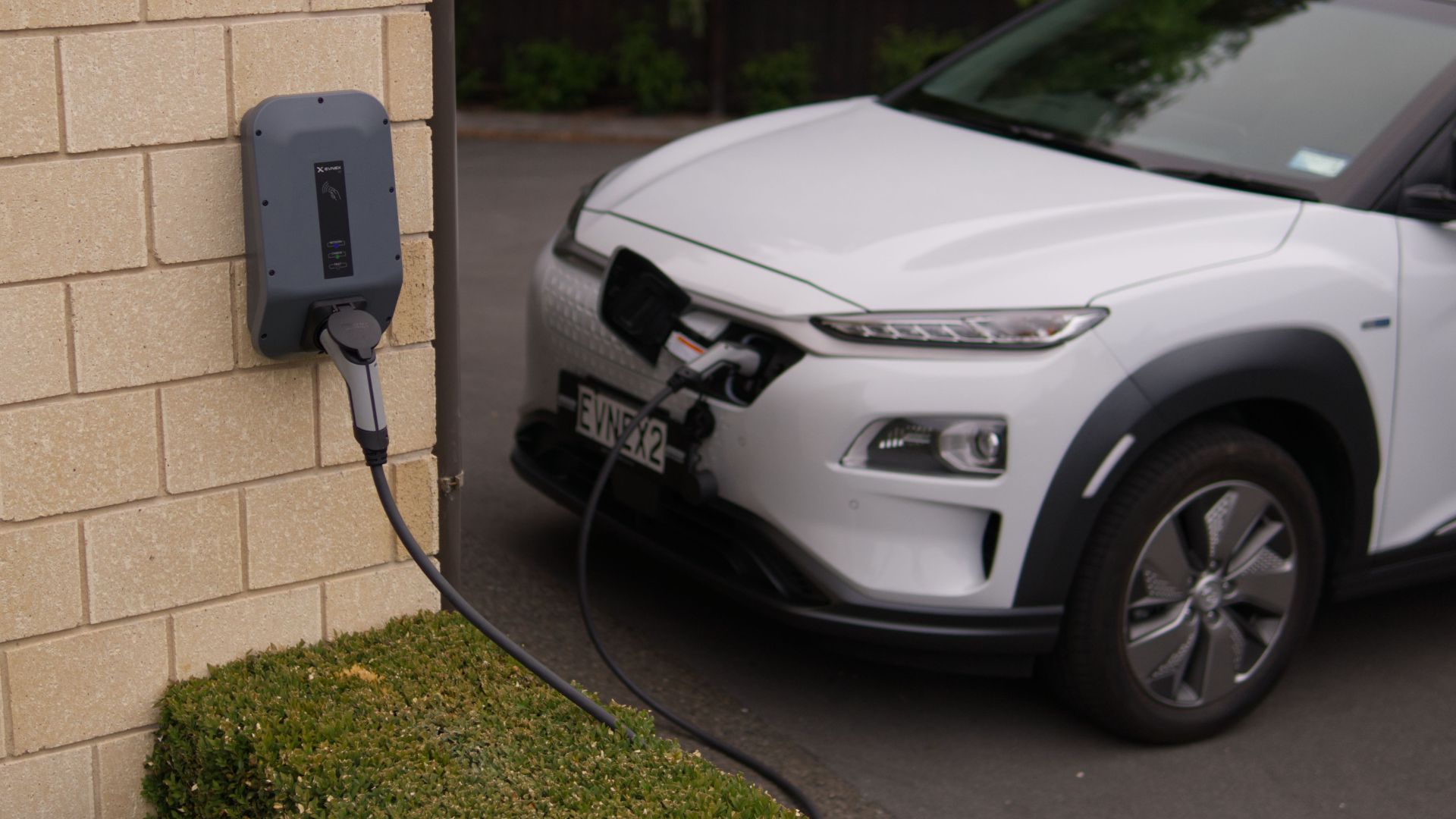 A white electric car charging at a station in Christchurch, New Zealand, showcasing modern eco-friendly transportation.