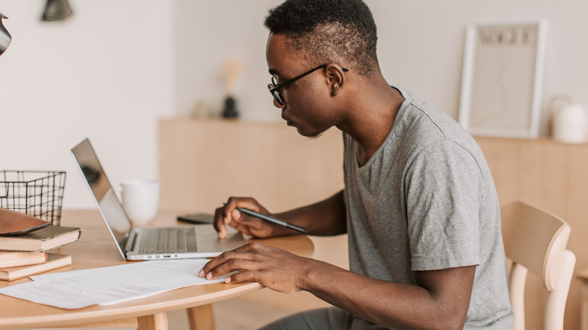Young man working remotely on a laptop indoors, using digital tools for communication.