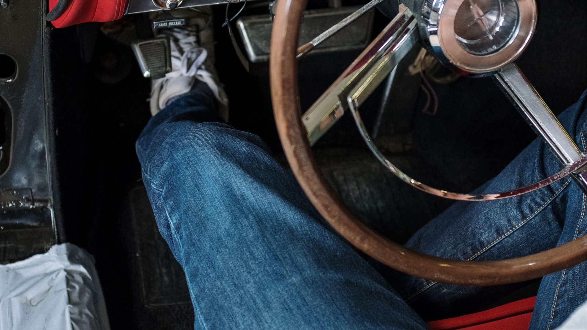 Close-up of a person driving a vintage car. Focus on the retro dashboard and steering wheel.