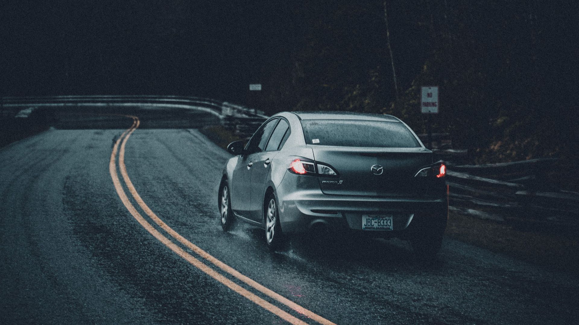 A car on a dark, wet road, creating a moody and dramatic scene.