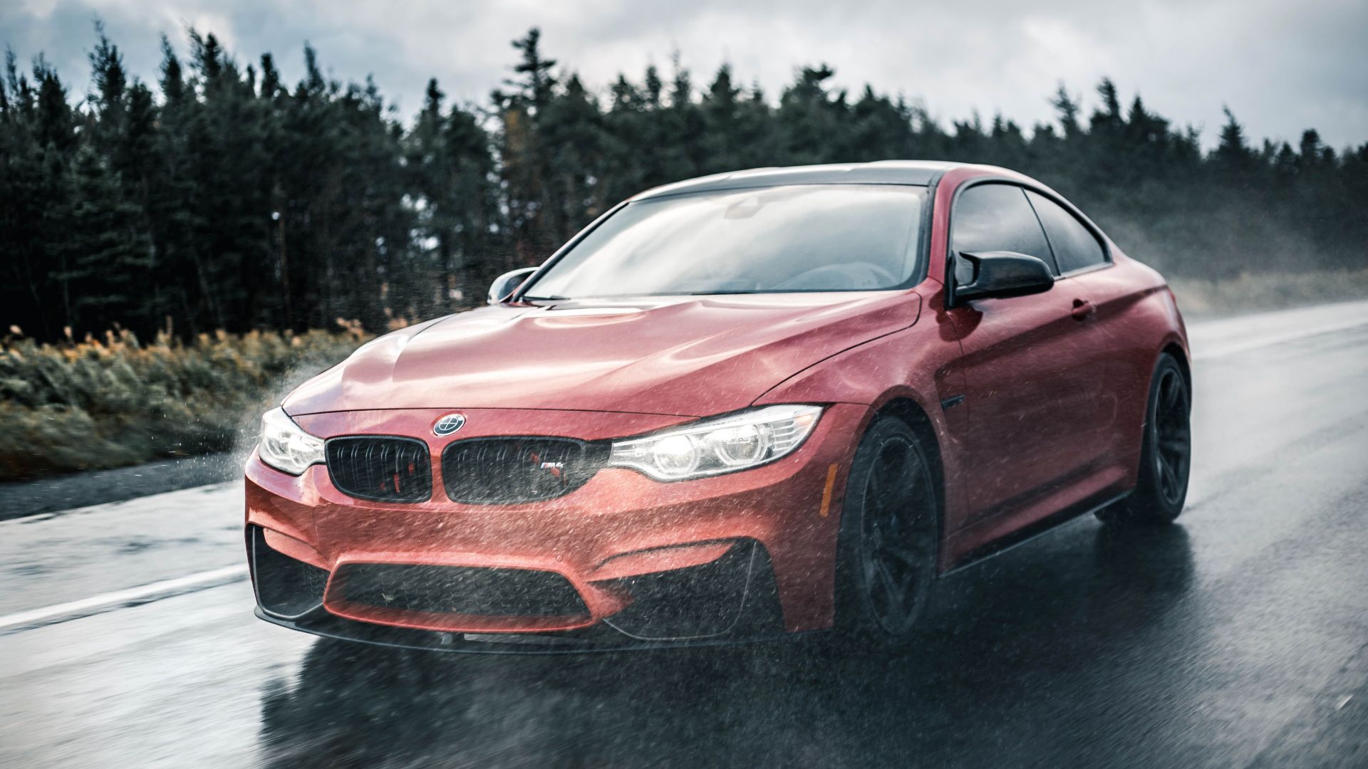 A sleek red sports car driving fast on a wet road with blurred motion and rain in the background.