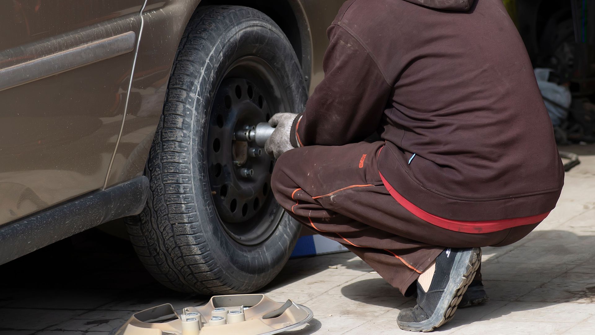 A mechanic working on a car tire, changing it in an auto repair shop.