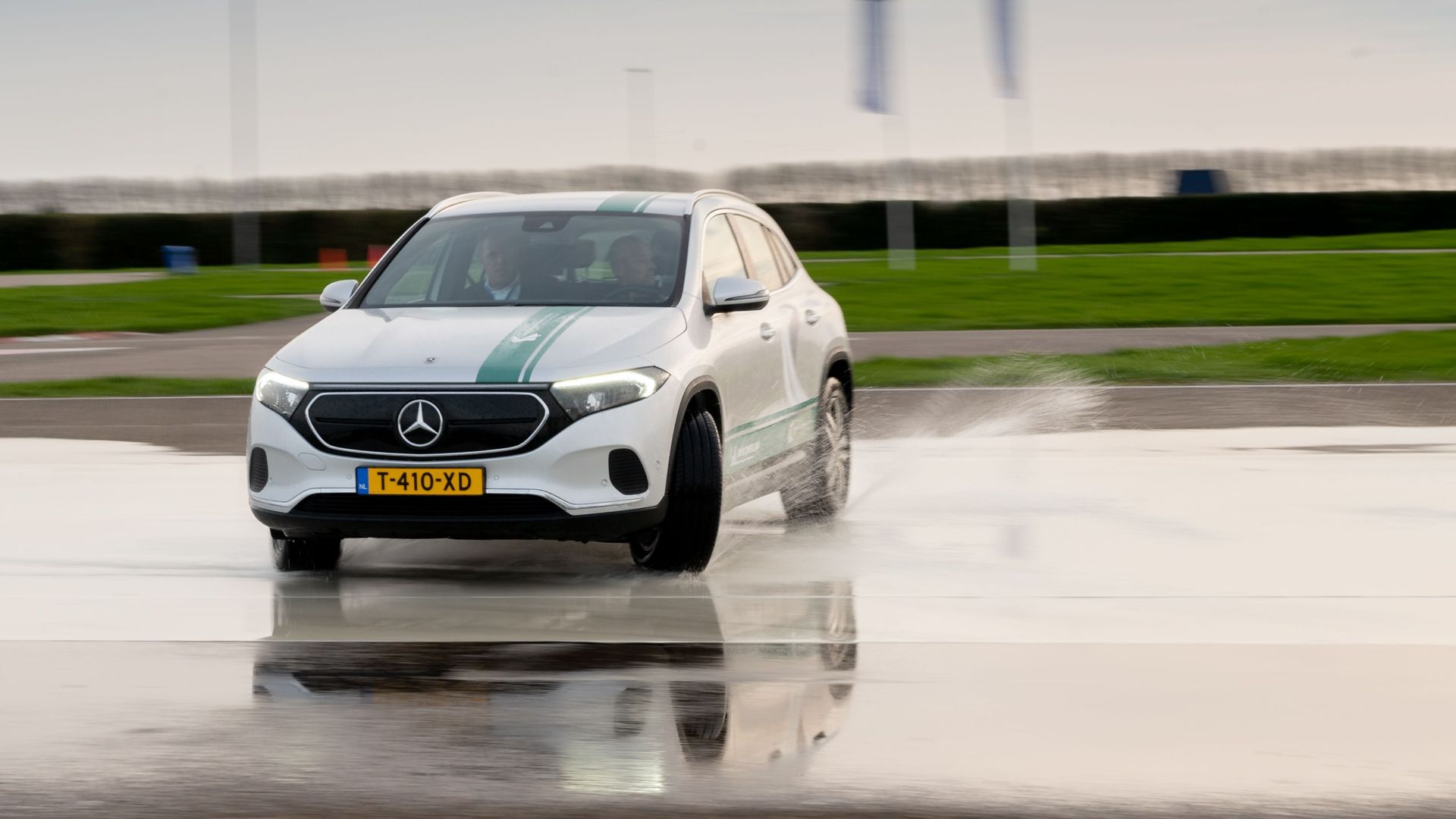 A silver Mercedes driving on a wet track with splash effect showcasing skid control technology.