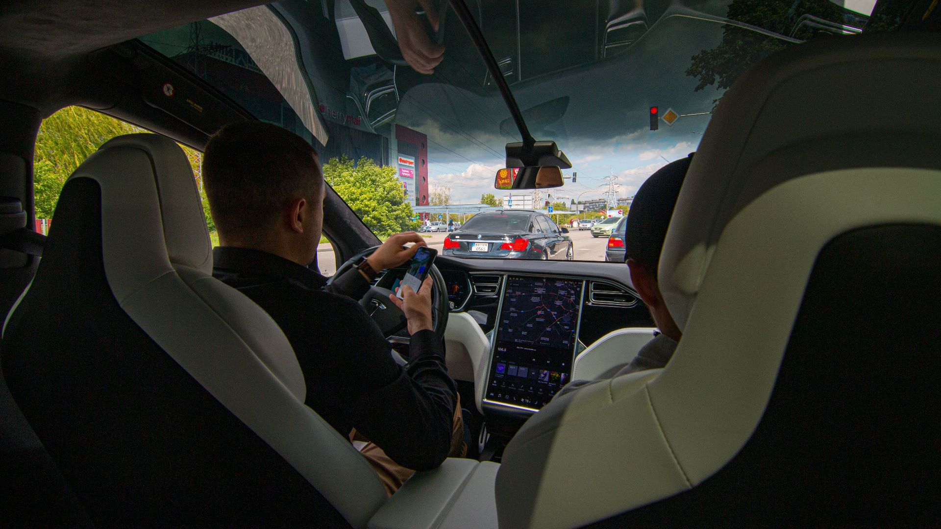 Inside a Tesla vehicle in city traffic, showcasing modern technology and urban driving.