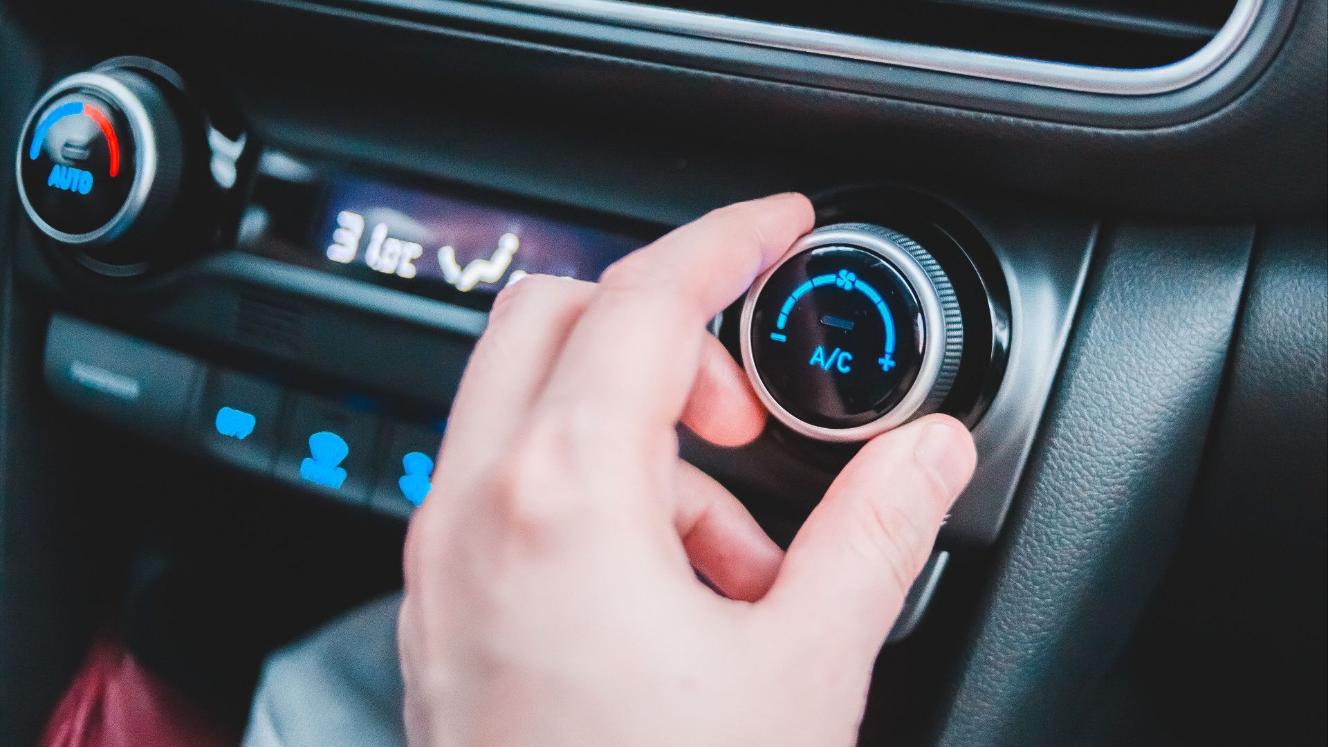 Crop anonymous person regulating temperature in car using controller on panel while sitting in car