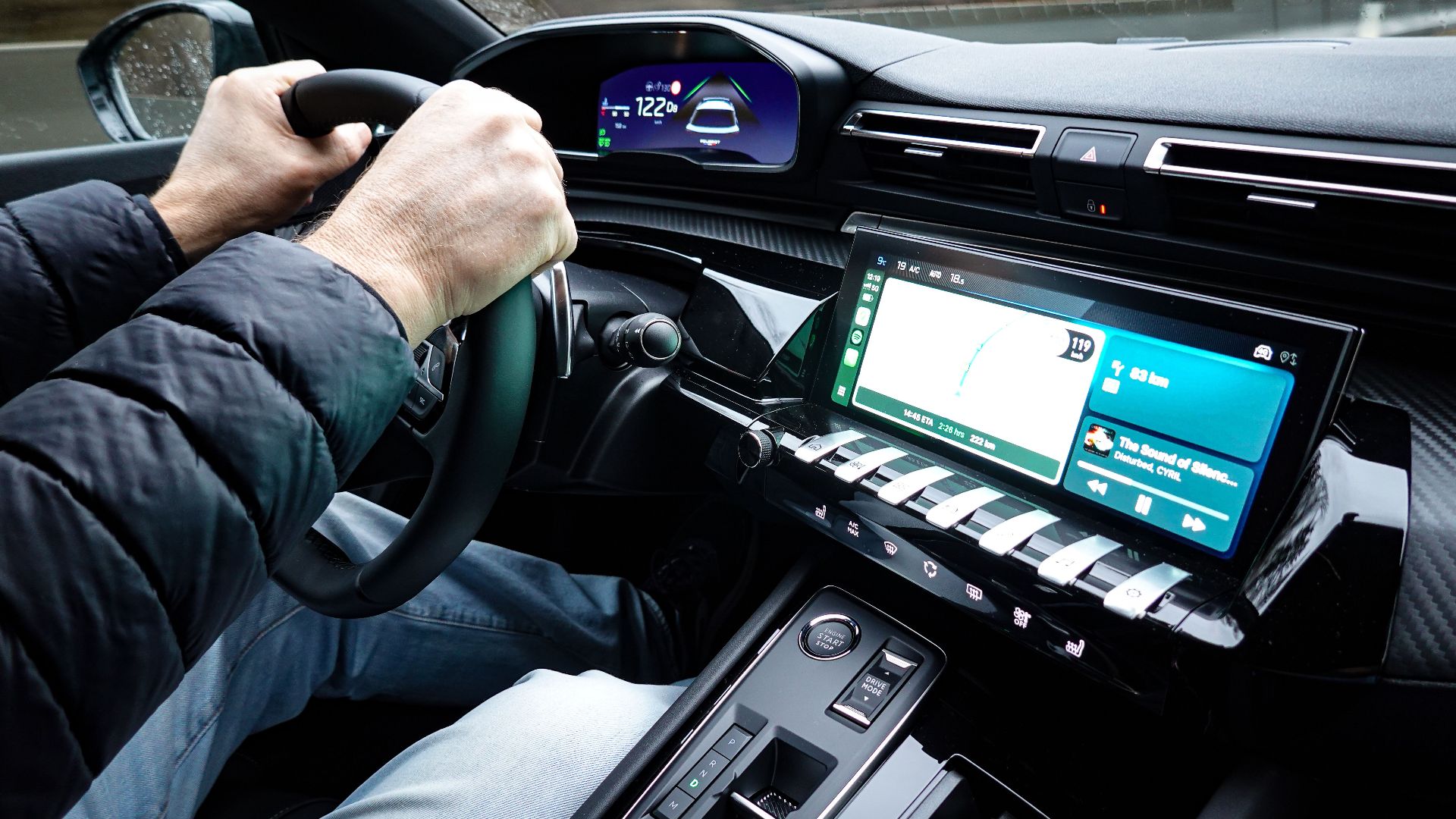 A detailed view of a car's interior with hands on the steering wheel, showcasing modern technology.