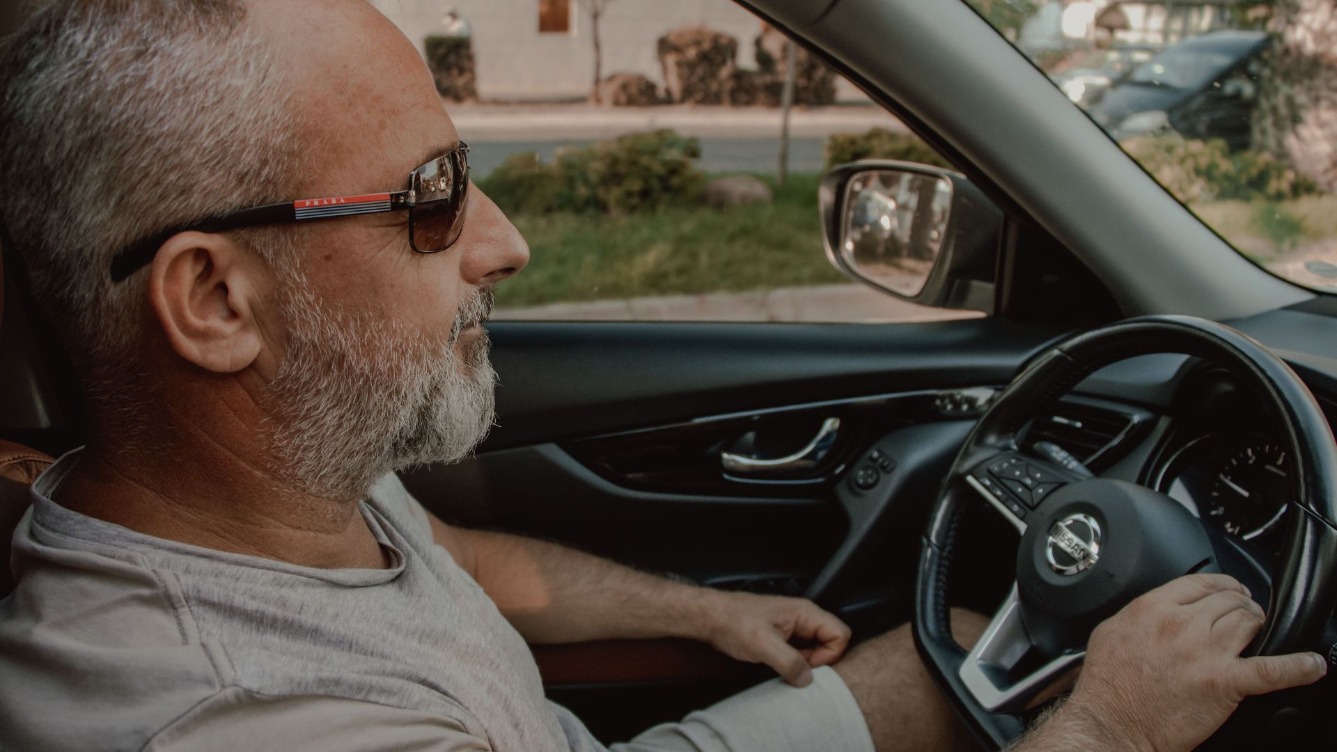 Middle-aged man driving a car wearing sunglasses, providing a relaxed and confident vibe.