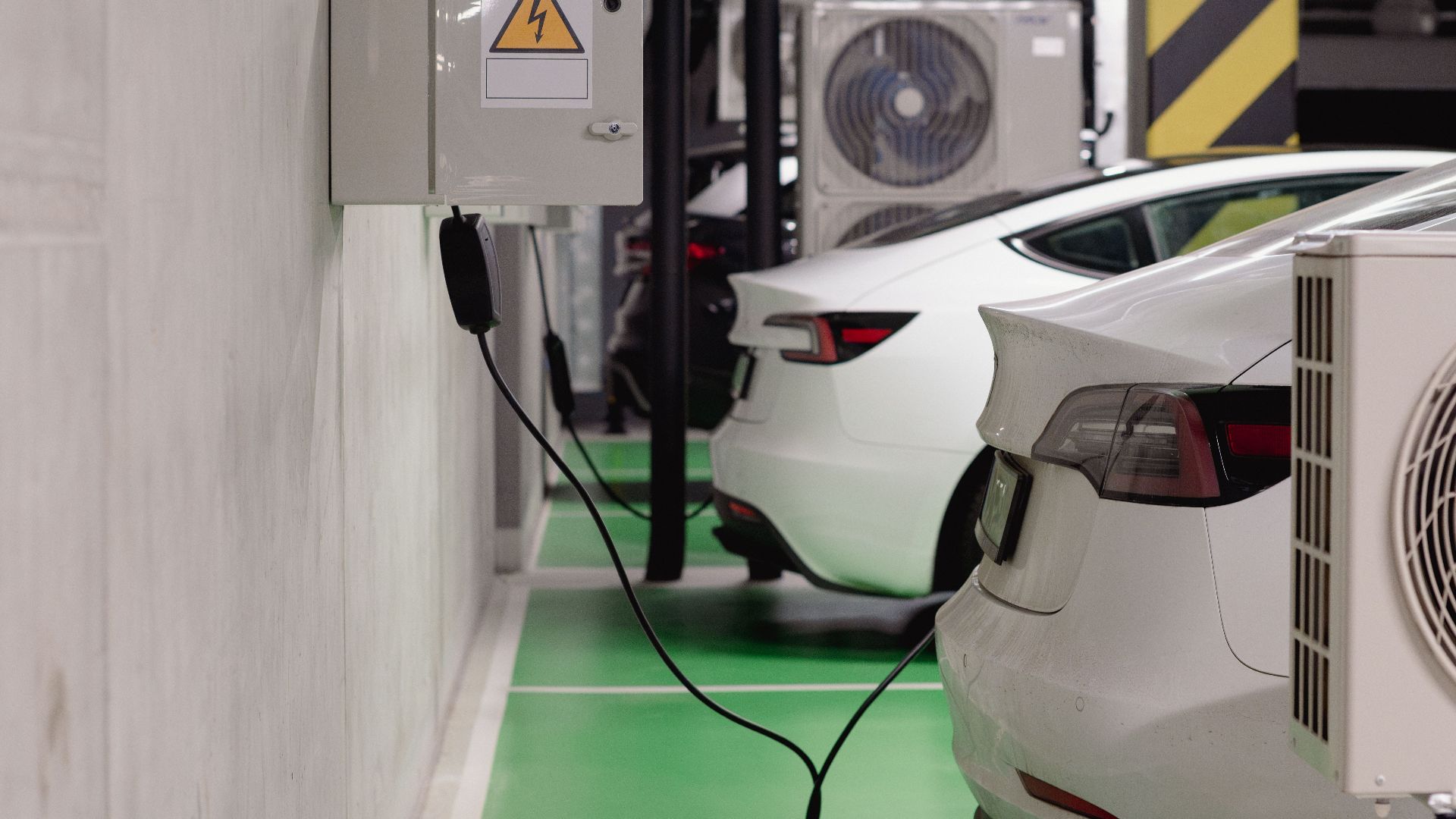 Electric vehicles charging at an indoor station in a modern underground garage.