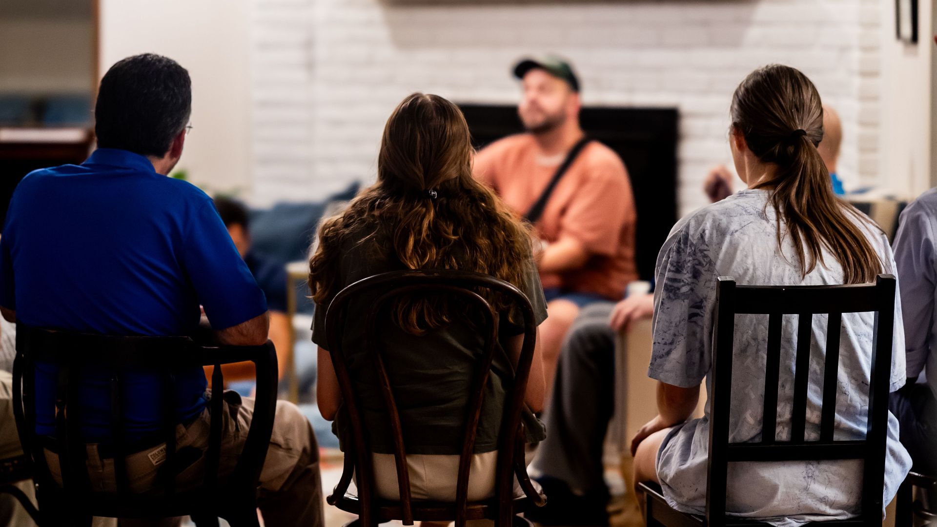A diverse group engages in a casual conversation in a cozy living room setting.