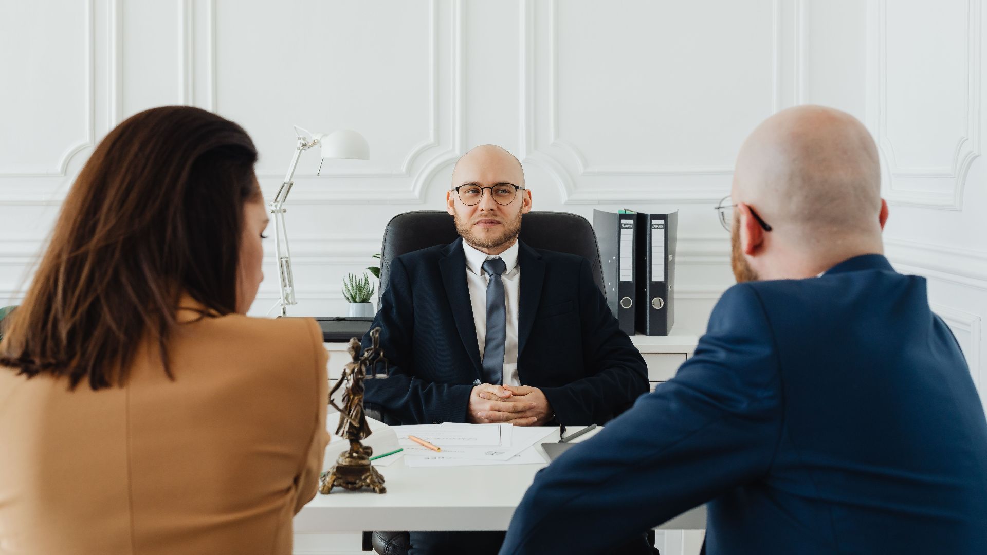 Lawyer meeting with clients in a formal office setting for legal consultation.