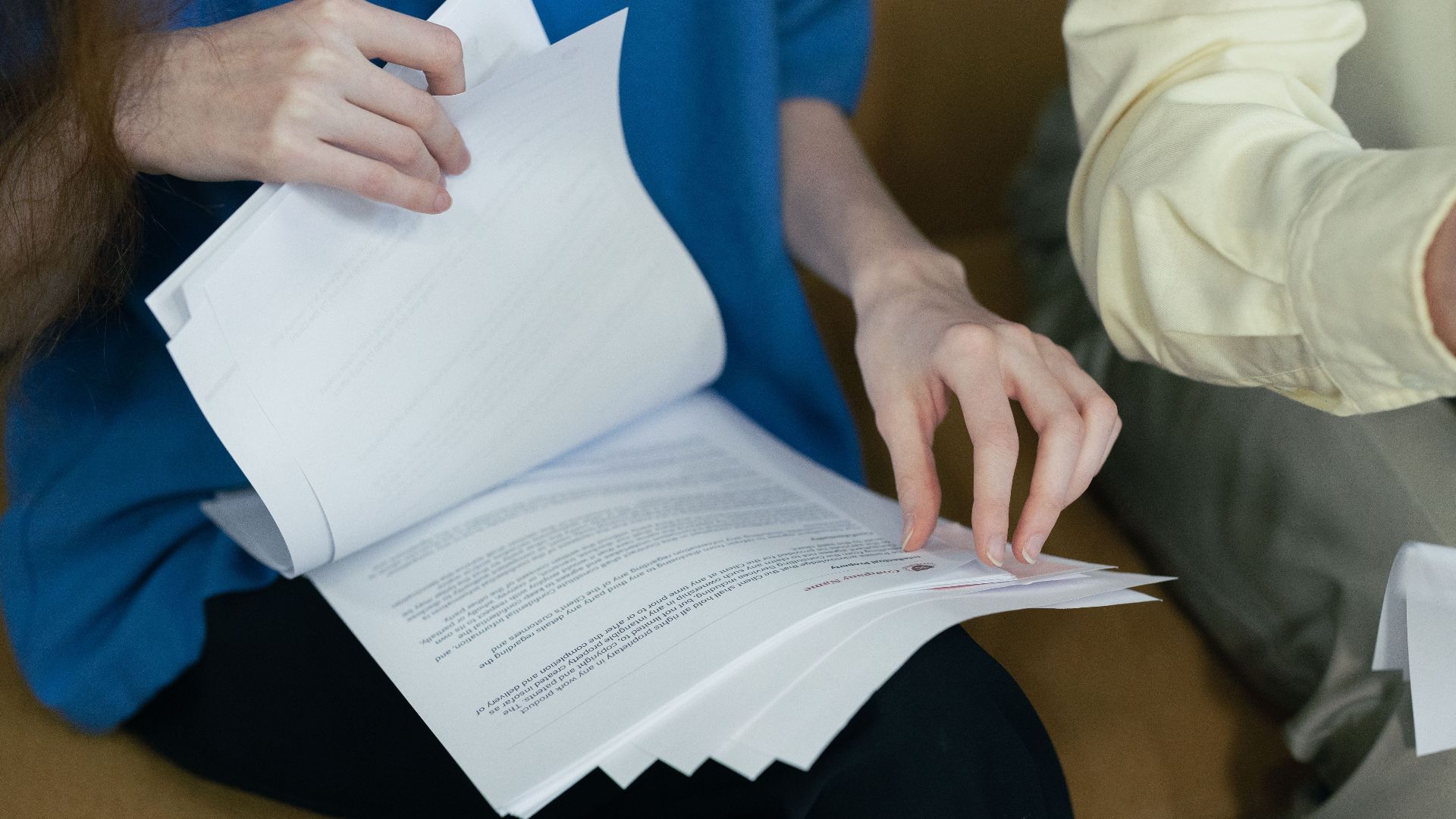 People in professional attire reviewing important documents together on a sofa.