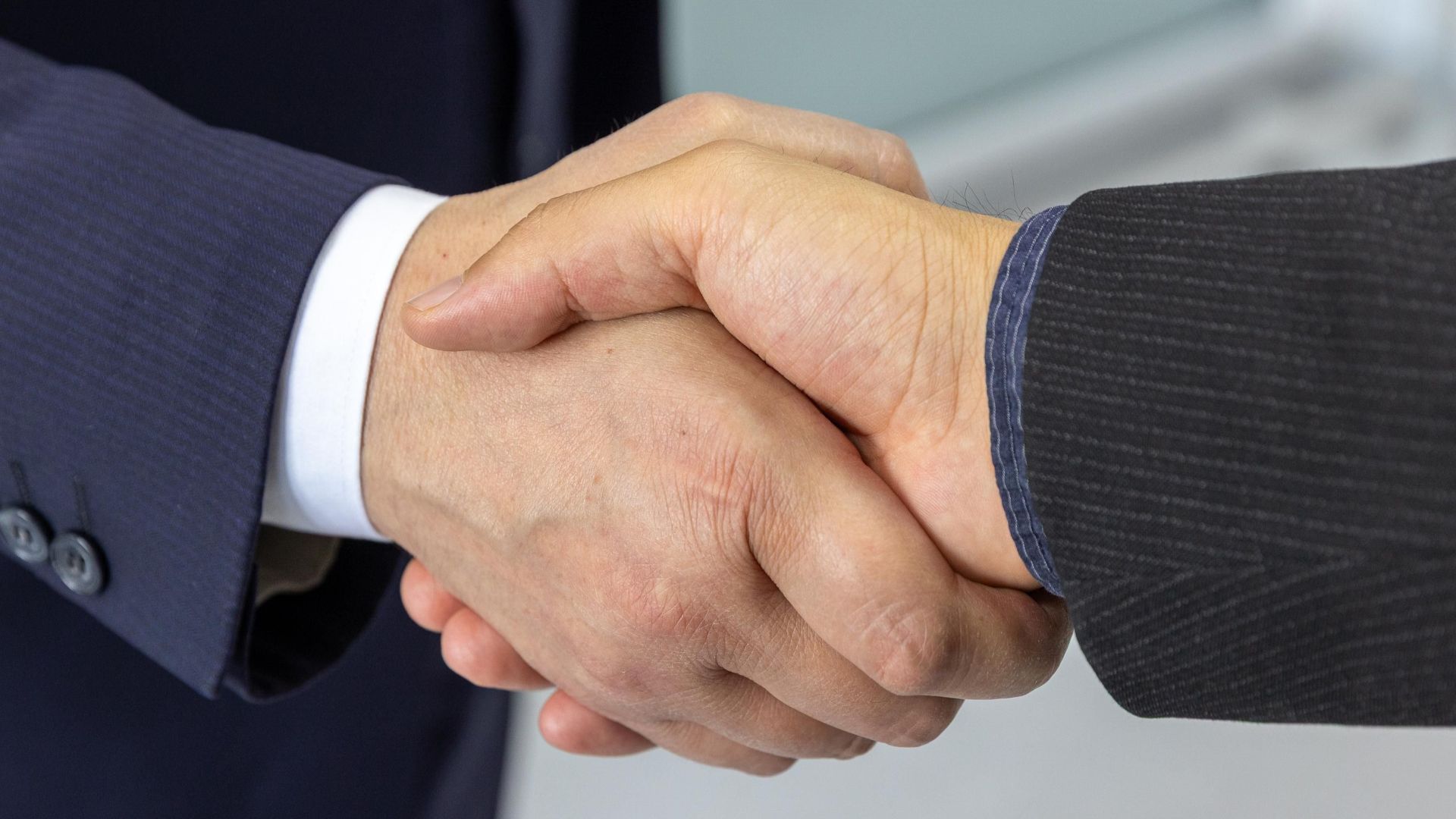 Close-up of two business professionals shaking hands, symbolizing partnership and collaboration.