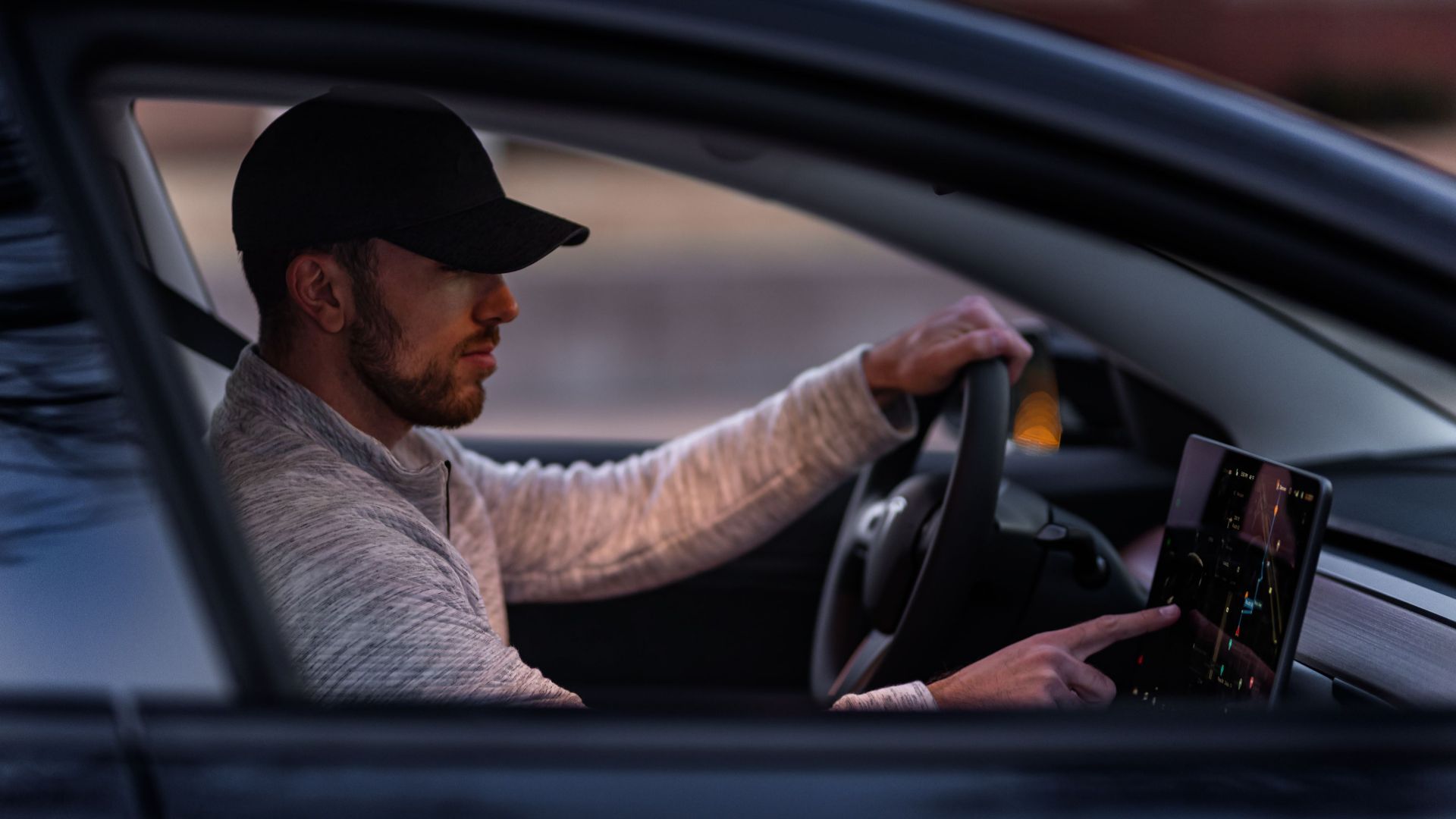 A man interacts with a touchscreen inside an electric car, driving through Dallas, TX.