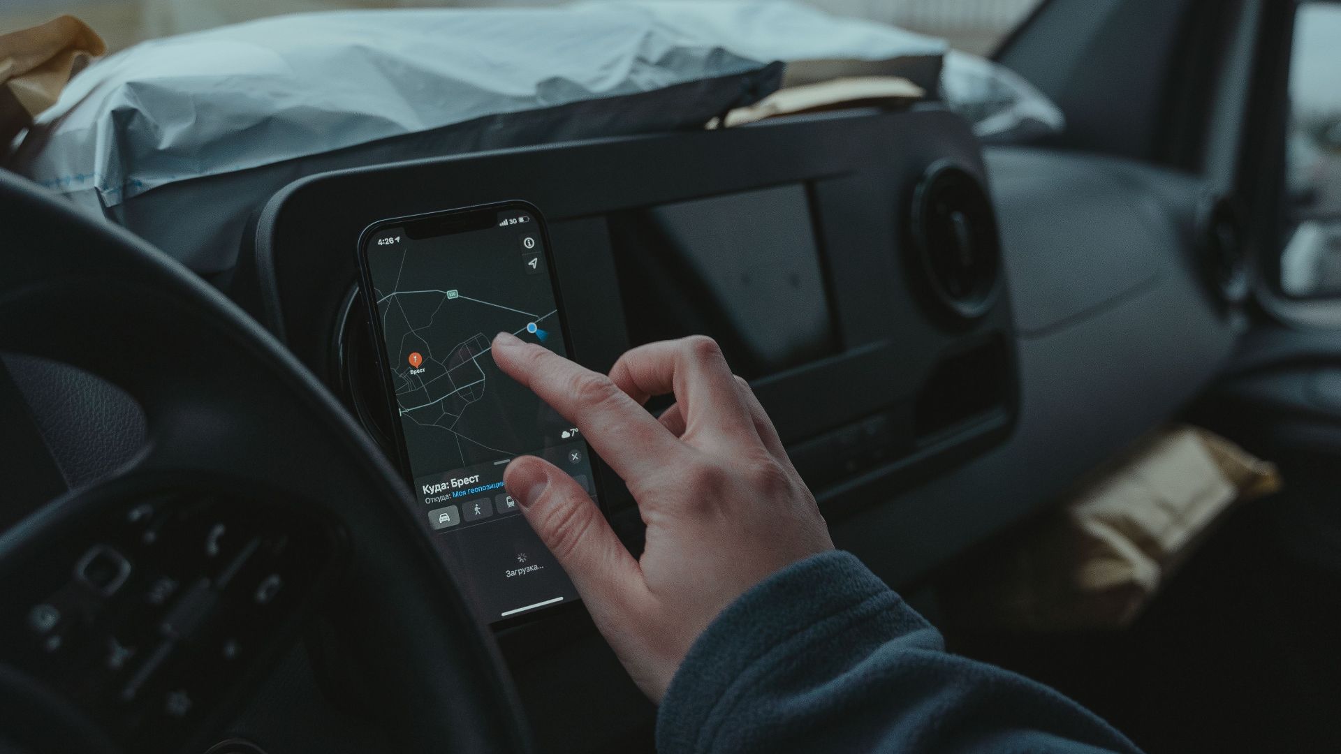 Hand using smartphone GPS inside car on a cloudy day. Technology and travel concept.