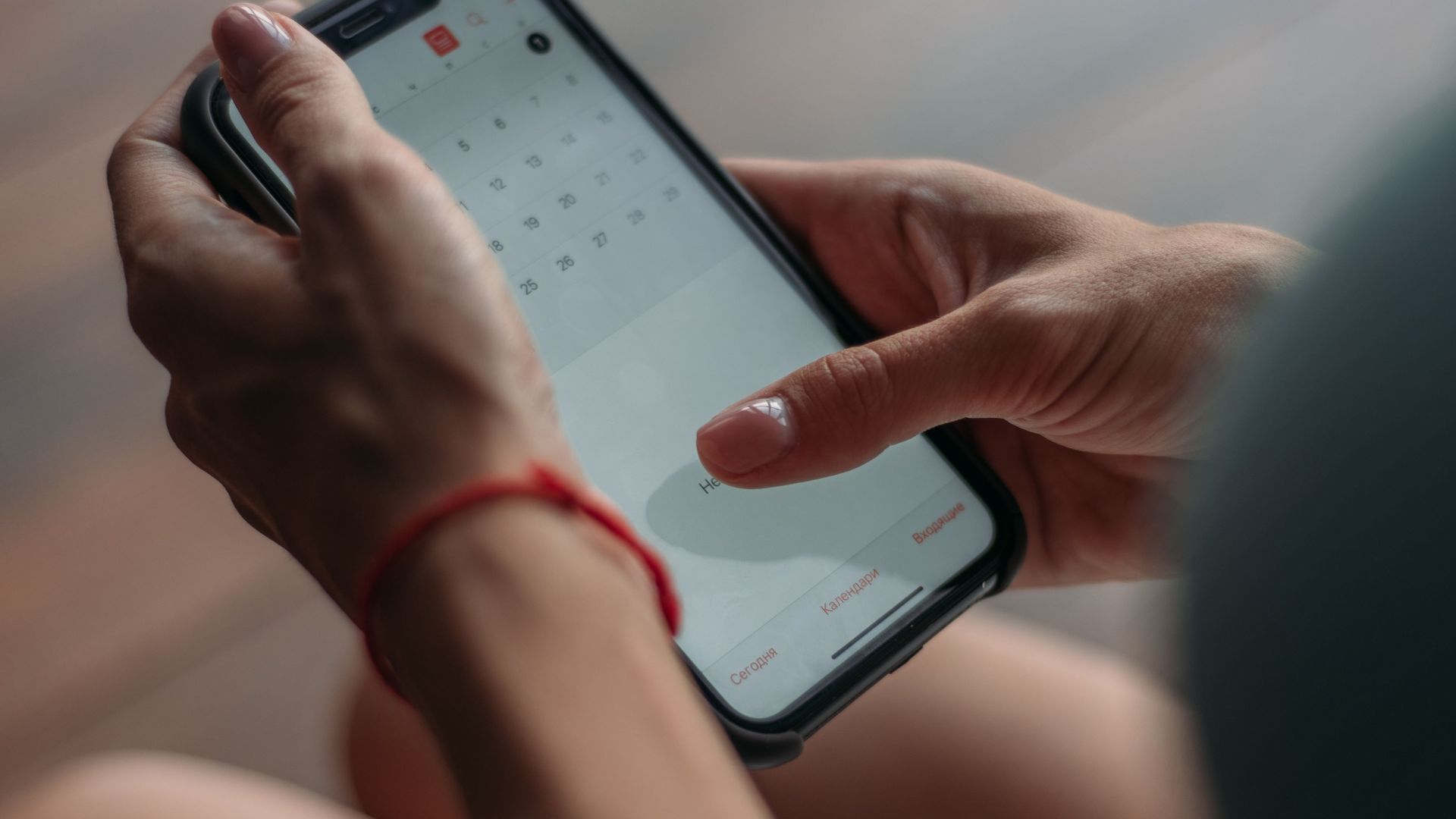 Close-up of a person using a smartphone to access the calendar app indoors.