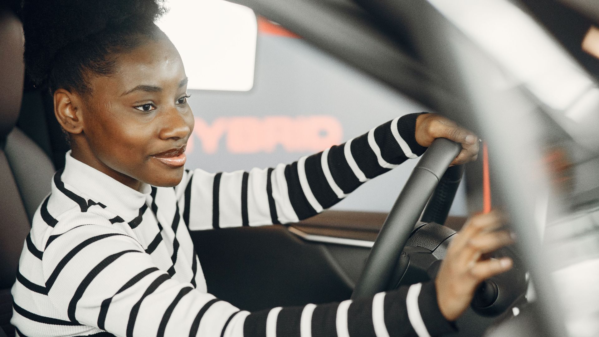 African American woman driving a car, smiling and confident behind the wheel from interior view.