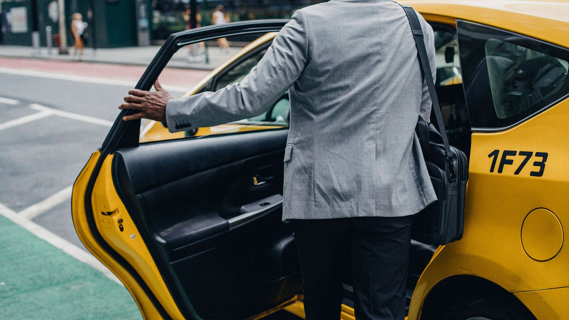 Back view crop unrecognizable African American male in formal outfit opening taxi door on modern city street