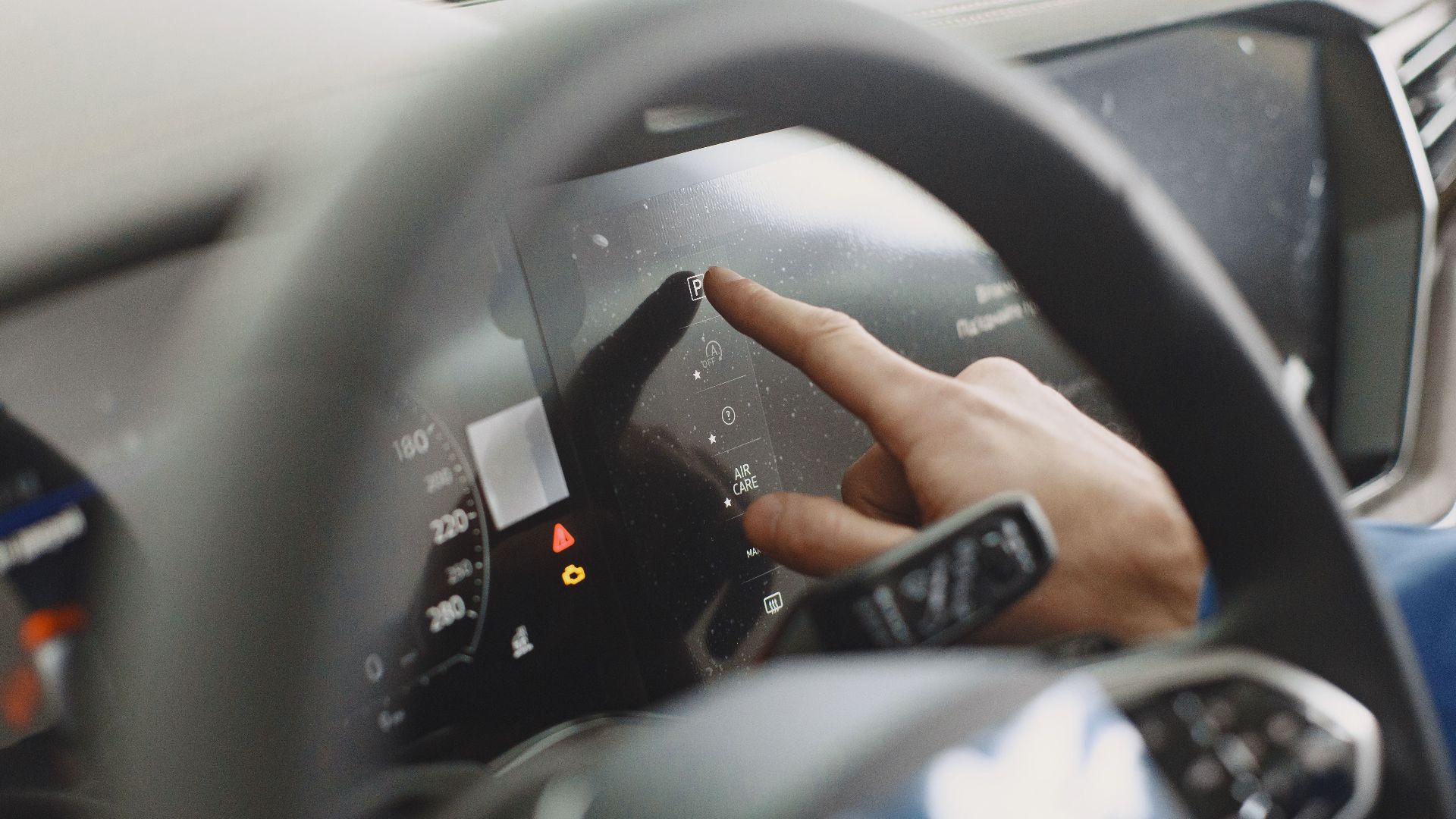 Close-up of a hand interacting with a car's digital dashboard. Modern technology and driving interface.