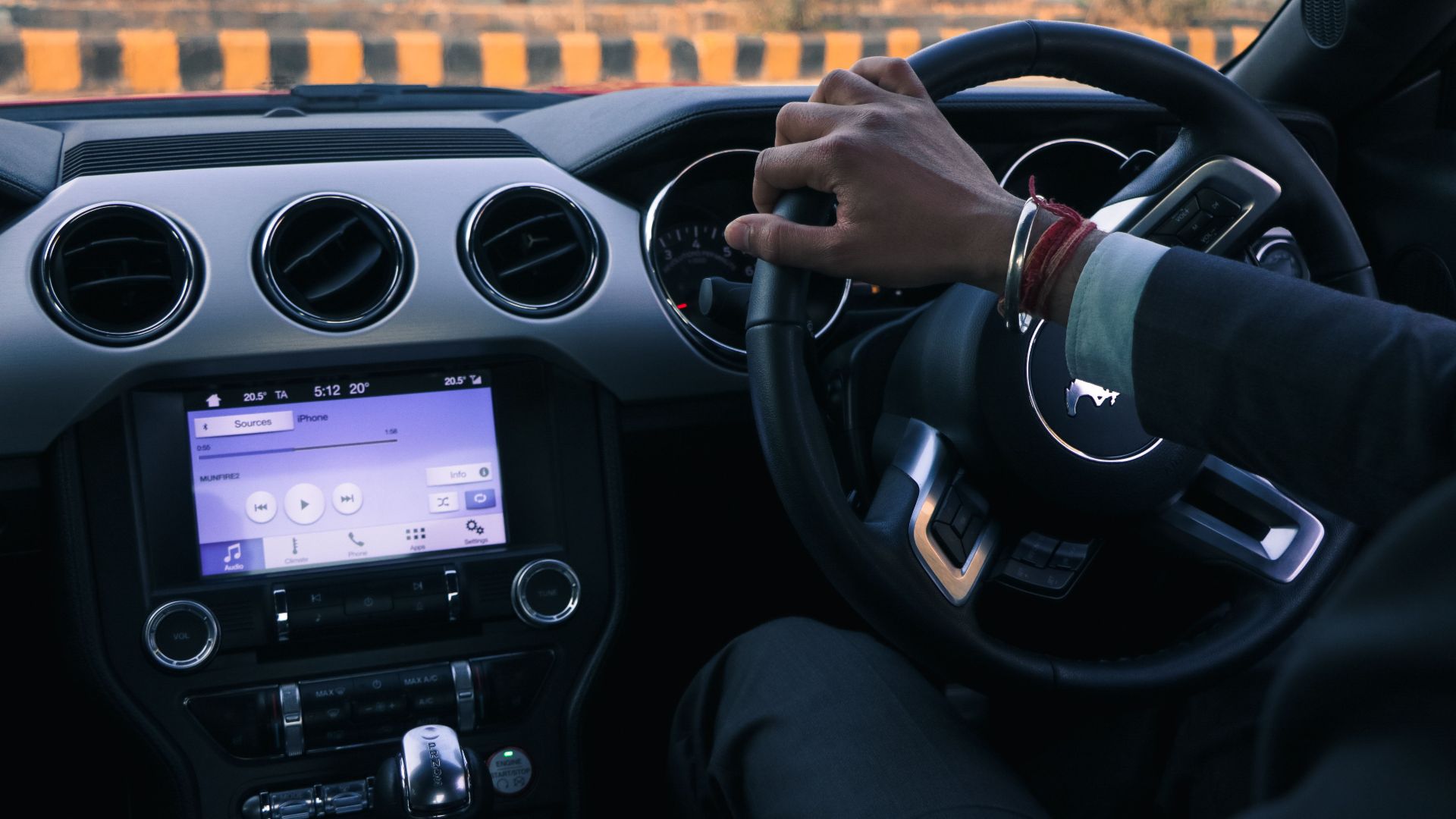 Close-up of a car interior with driver's hand on steering wheel in Delhi, India.