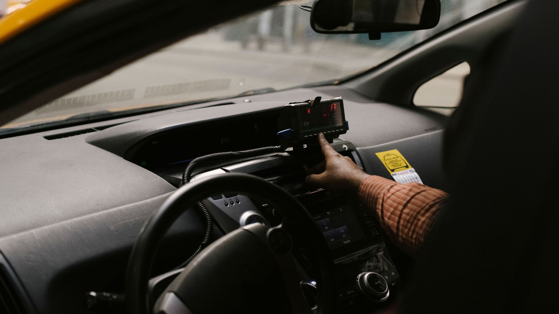 Anonymous ethnic male driver with steering wheel using GPS navigator to search direction for drive on street in city during work