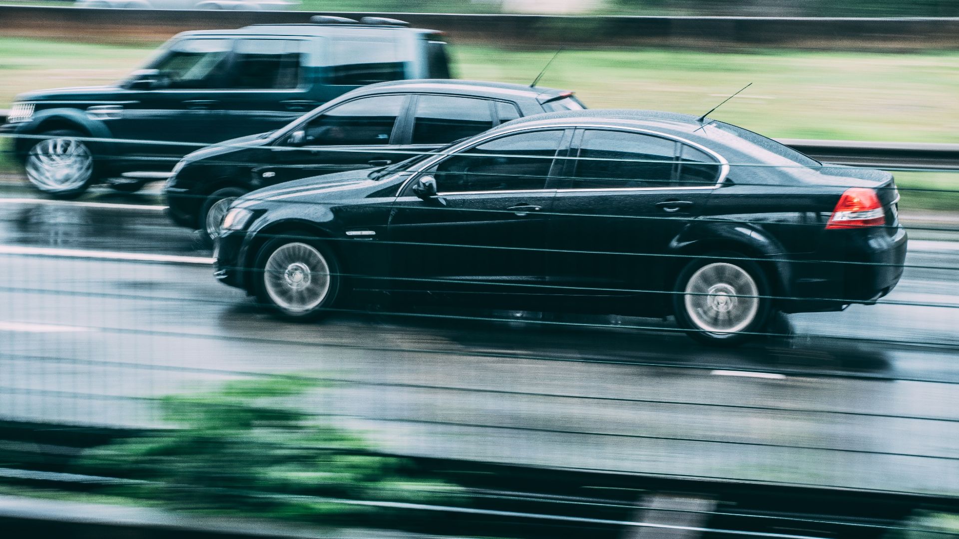 Blurred image of two cars racing on a wet highway, highlighting speed and motion.