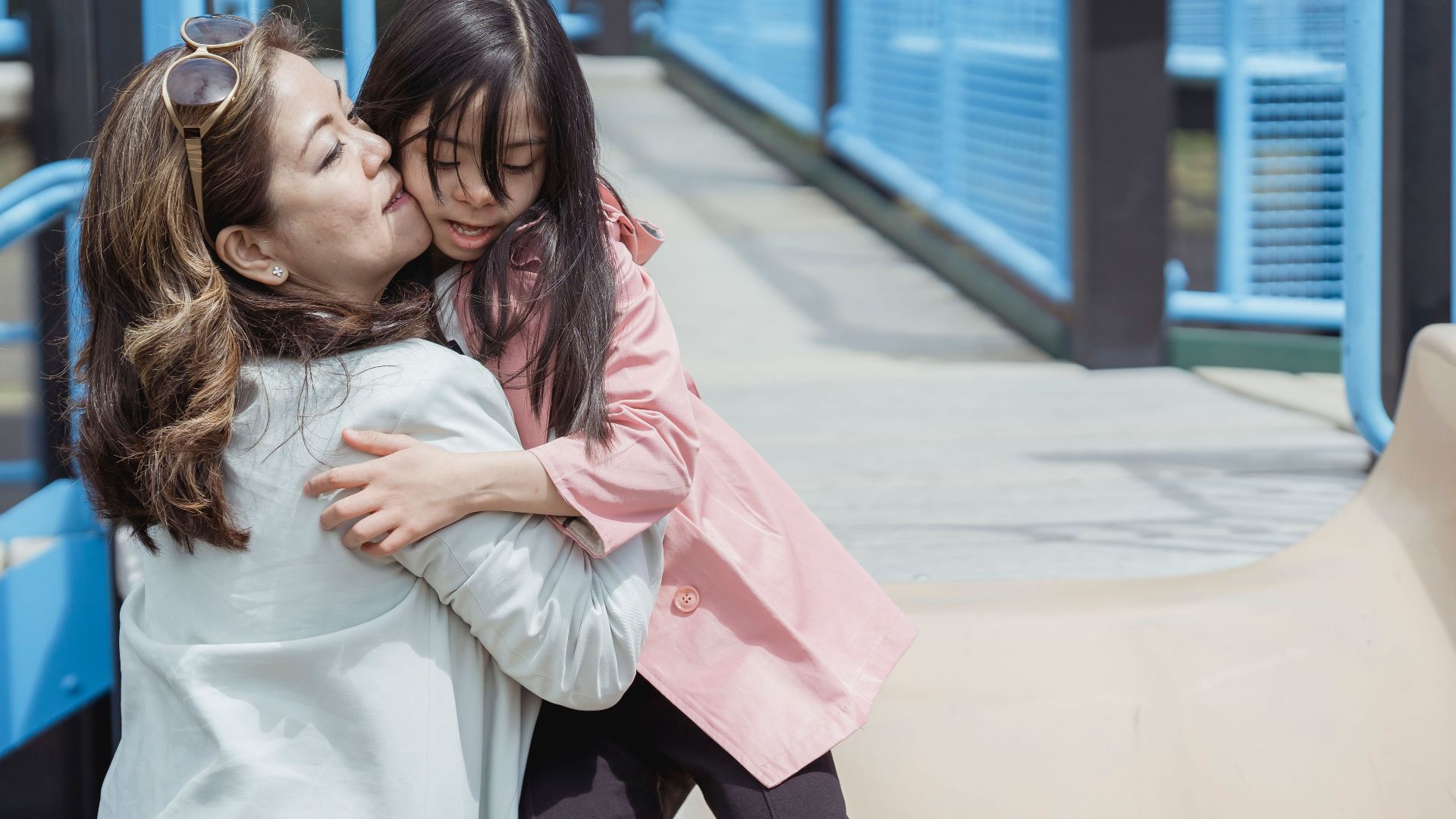 A heartwarming moment between a mother and daughter enjoying time together at a sunny playground.