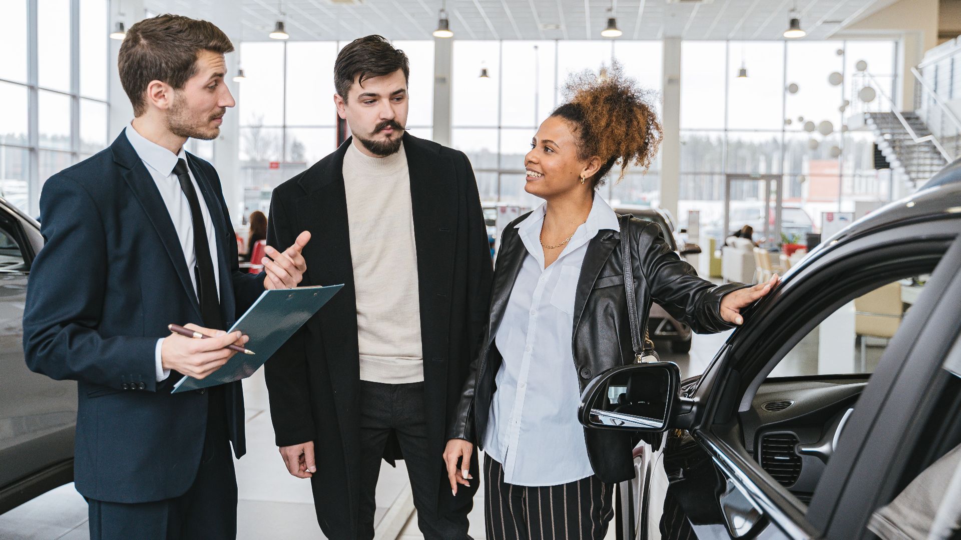 A diverse team of adults discussing a car purchase in a dealership showroom.
