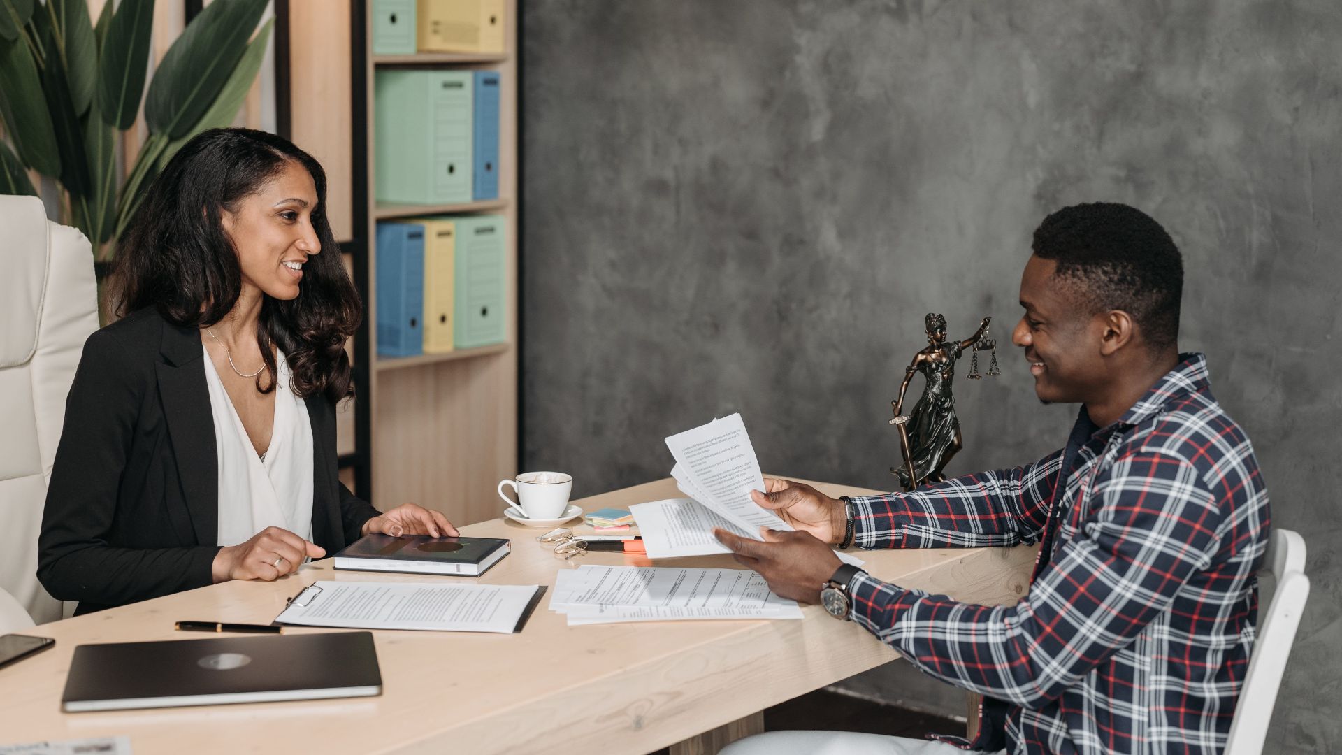 Two professionals having a discussion in a stylish office with paperwork and a laptop.