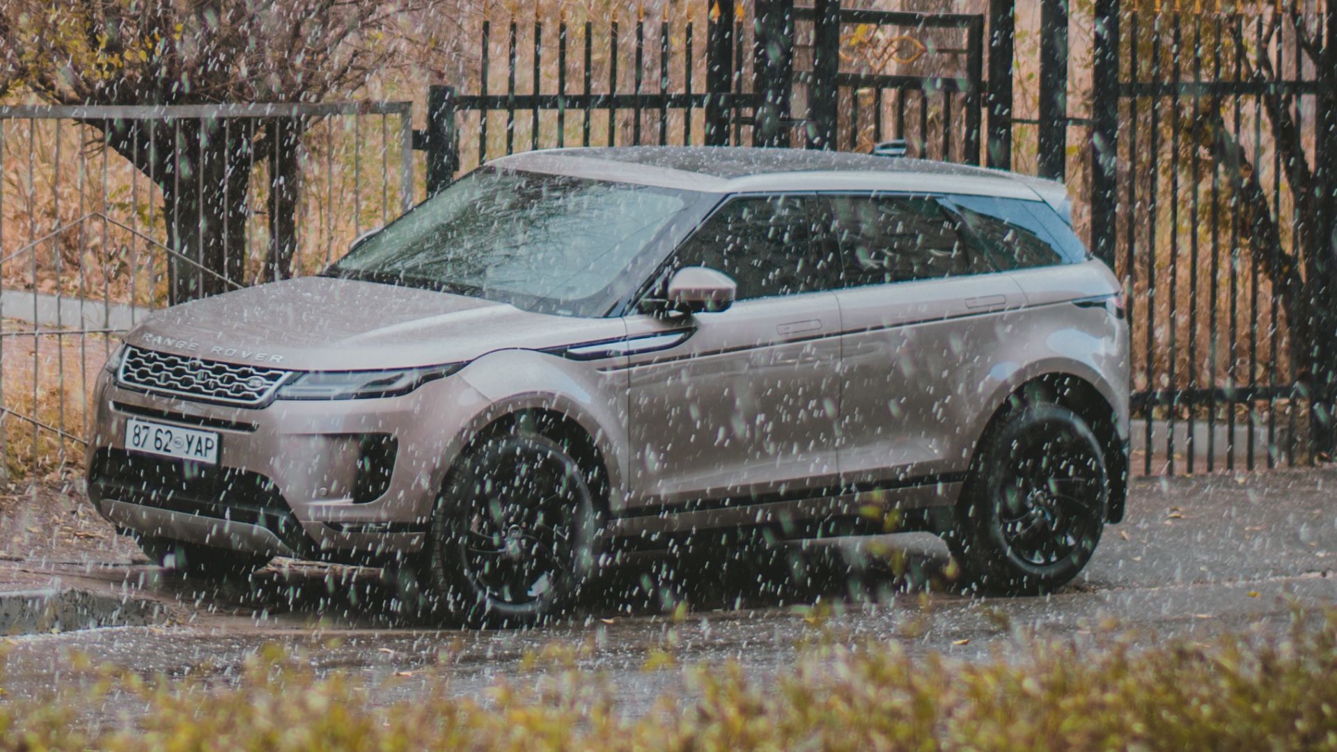 A sleek SUV parked on a rainy street in Ulaanbaatar, Mongolia surrounded by autumn trees.