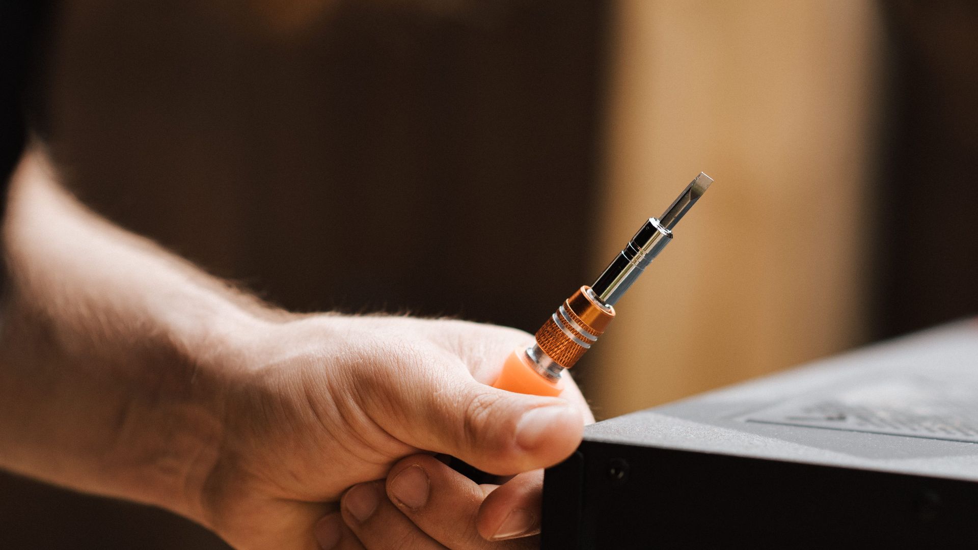 Crop anonymous focused male observing detachable connector in studio in spacious apartment in soft daylight
