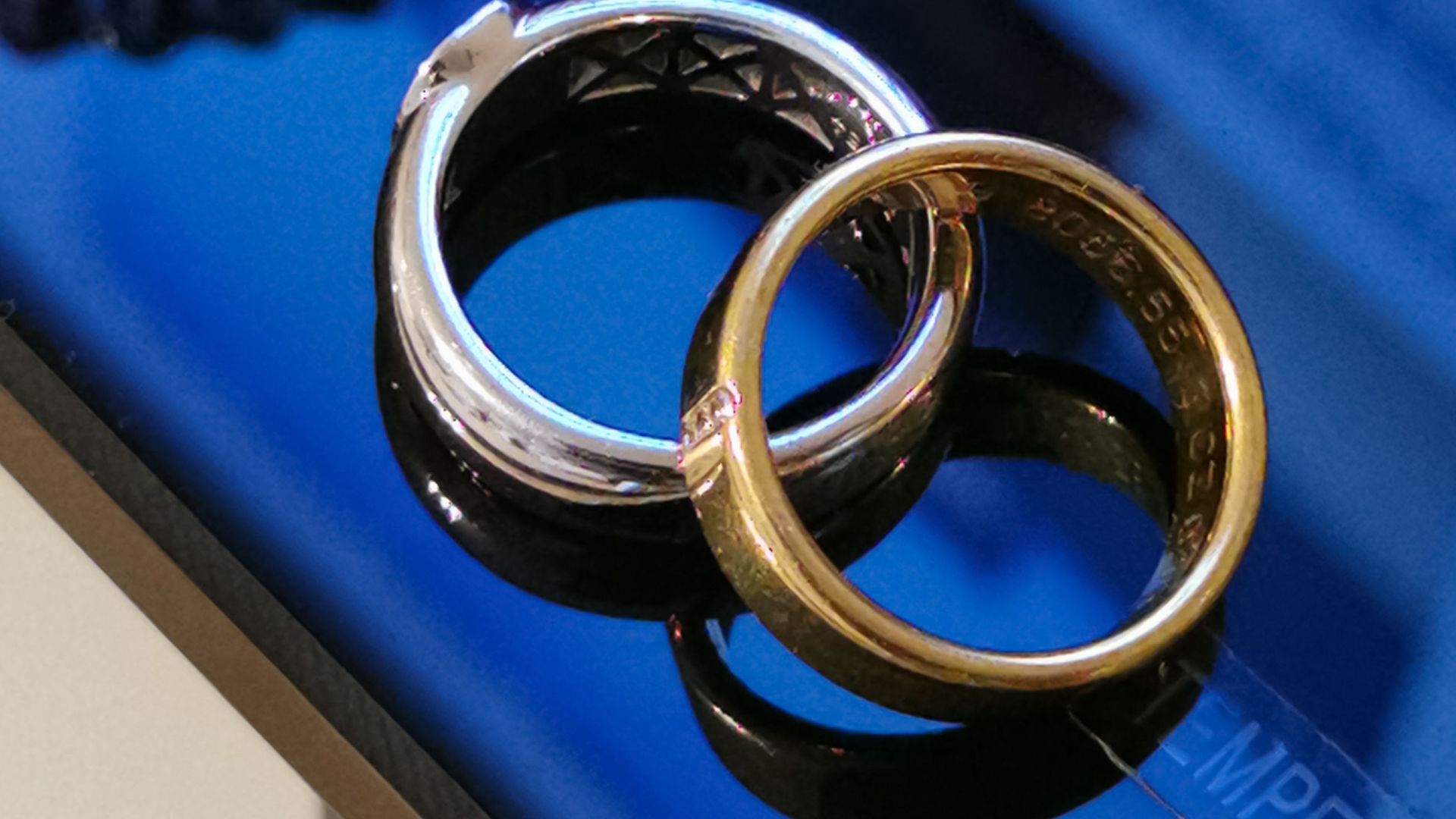 A detailed close-up of silver and gold rings on a reflective surface, showcasing intricate designs.