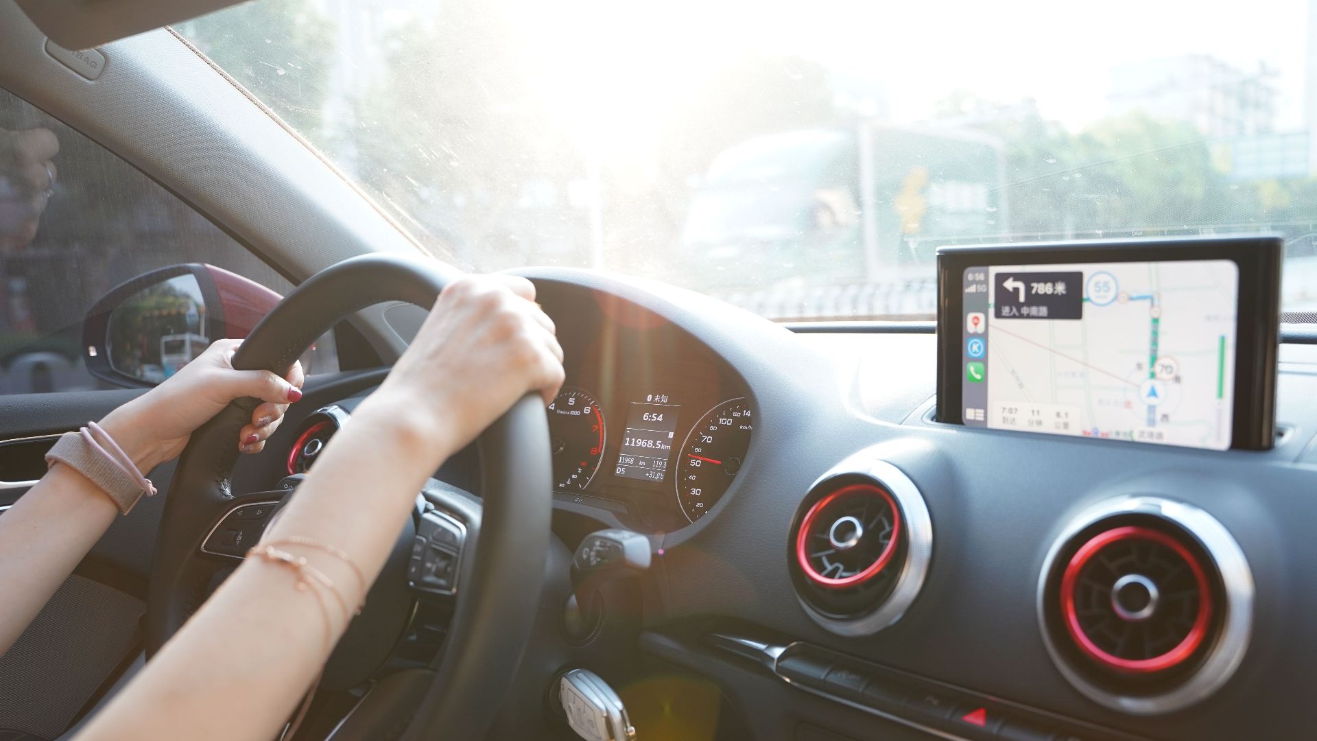 Hands on steering wheel using GPS navigation inside car during road trip.