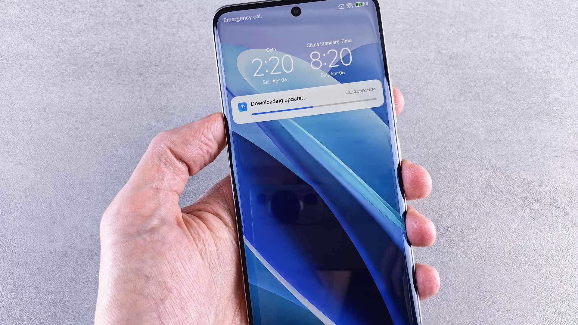 Close-up of a hand holding a smartphone with a downloading update notification on the screen.