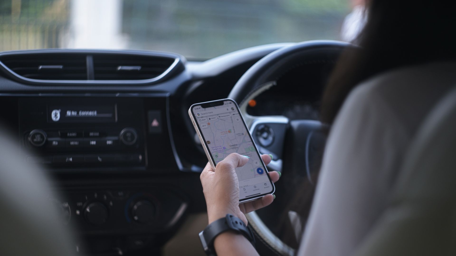 A woman holding a cell phone while driving a car