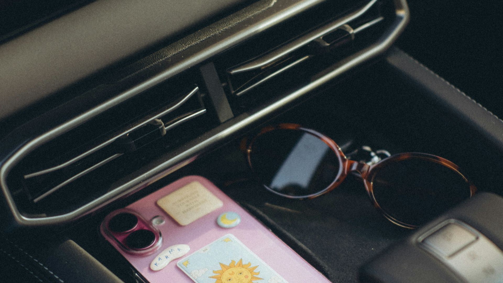 Phone and sunglasses in a car console.