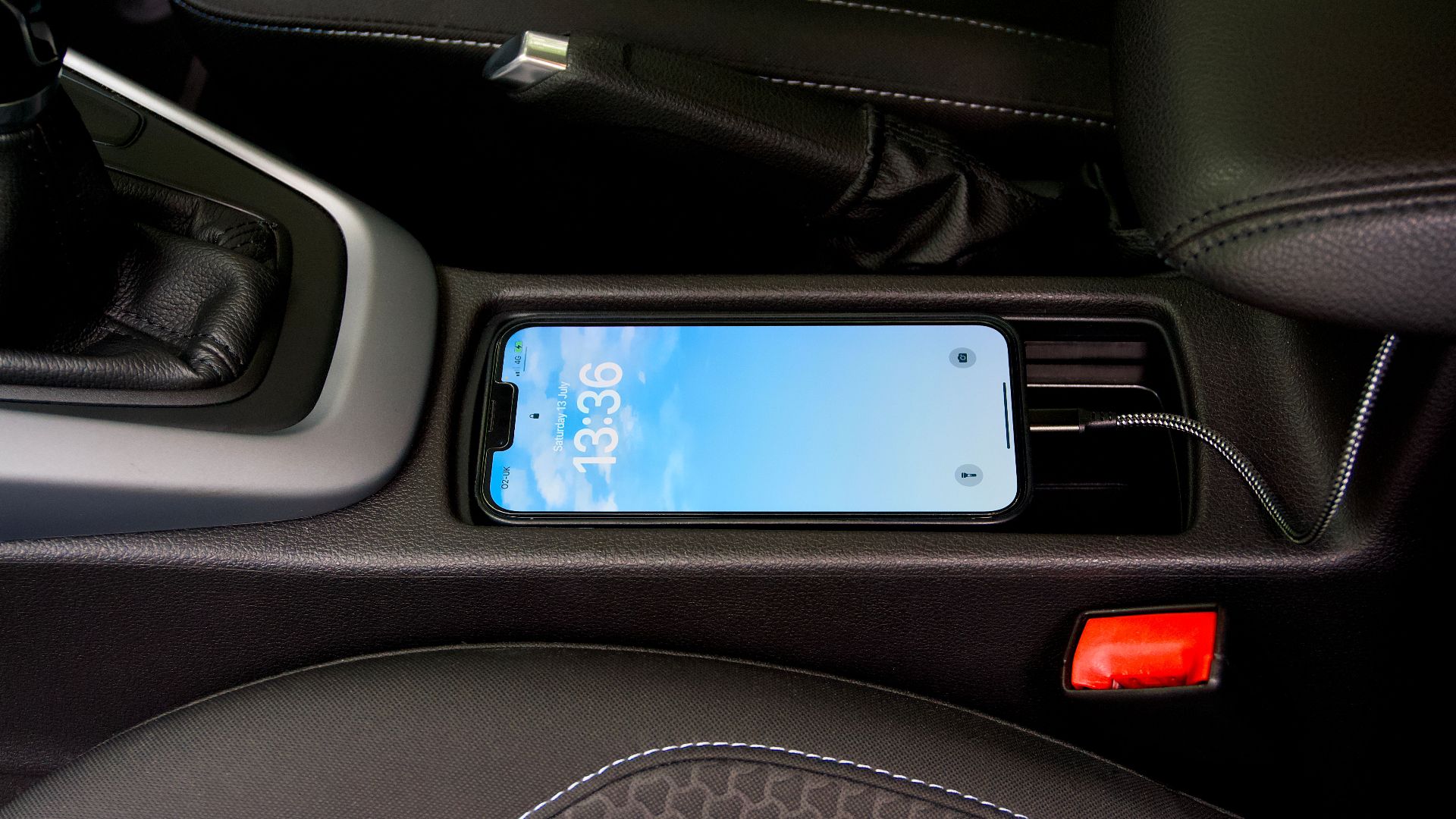 A smartphone charging in a car's central console, showcasing modern automotive technology.