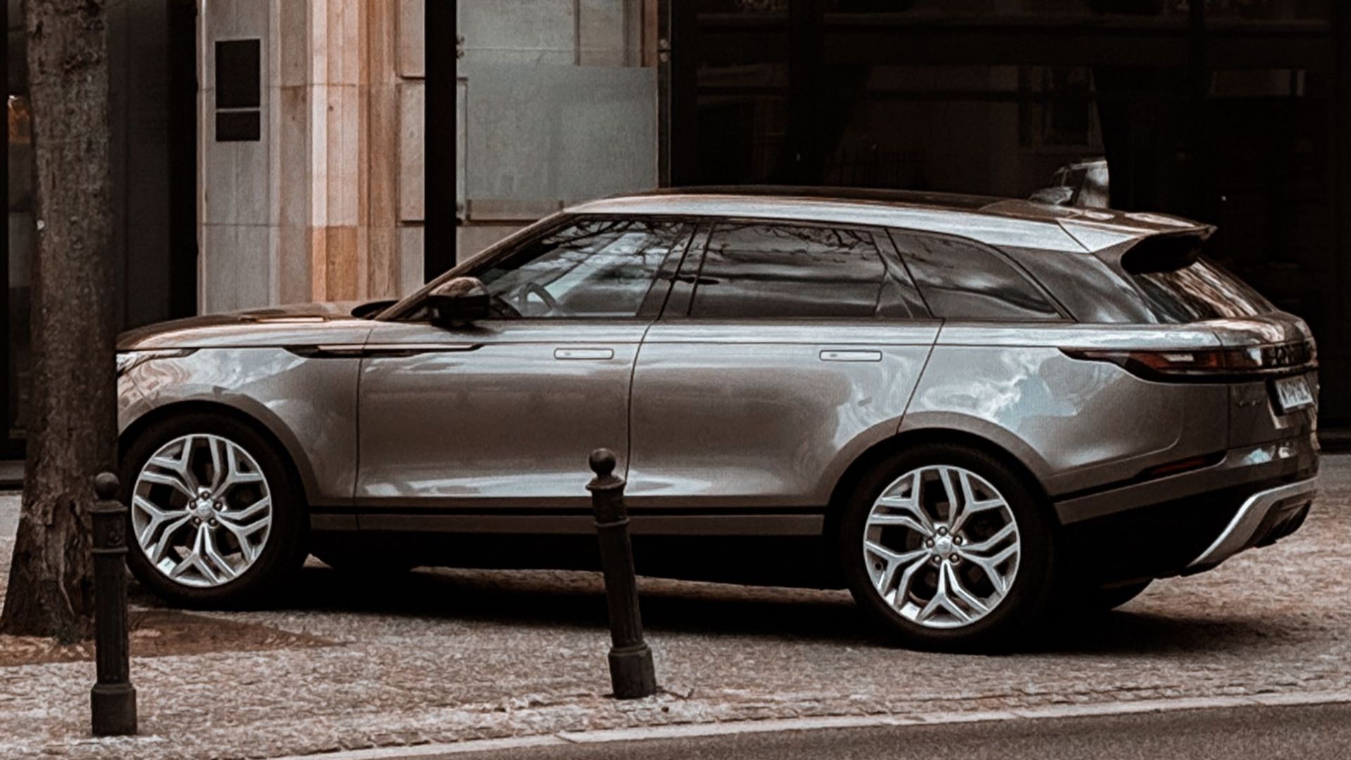 A sleek luxury SUV parked by a modern building on a city street in Warsaw, Poland.