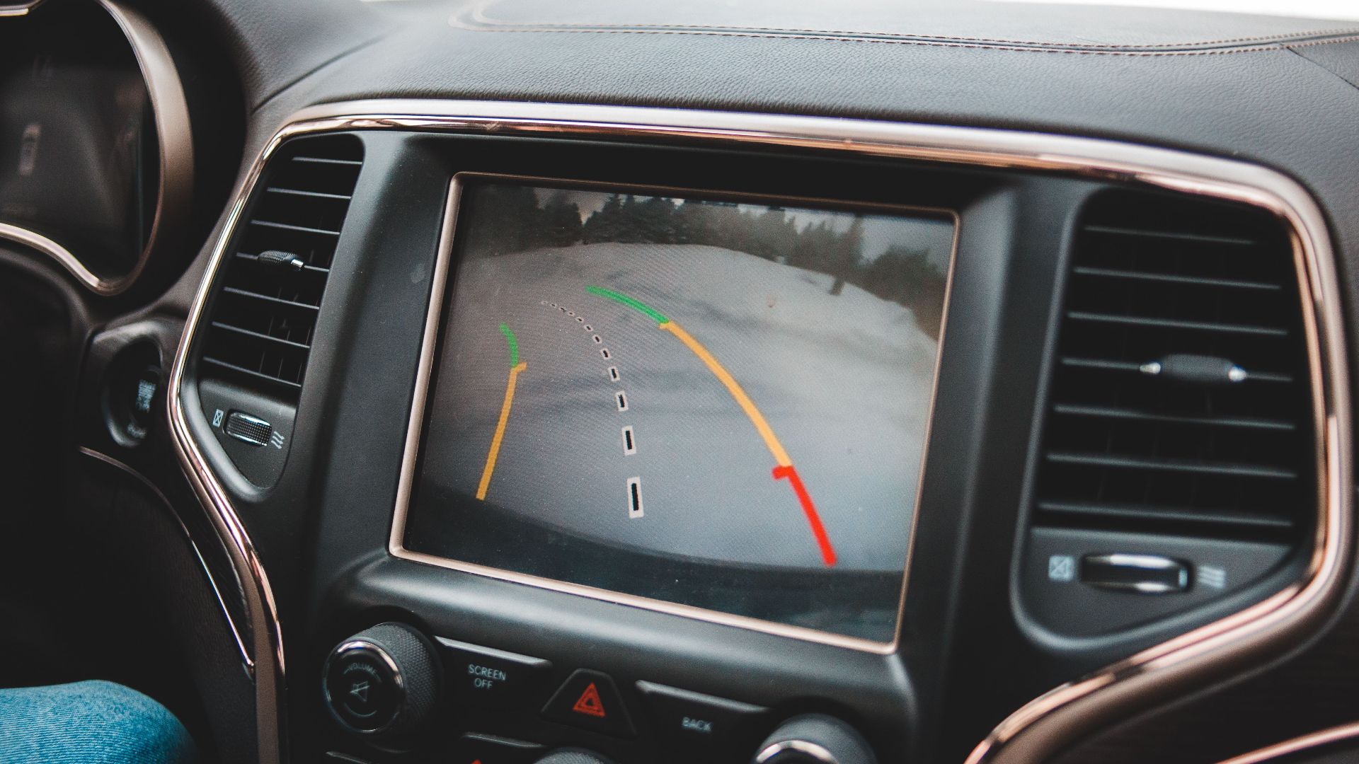 Close-up of a car's dashboard showing a rearview camera display for parking assistance.