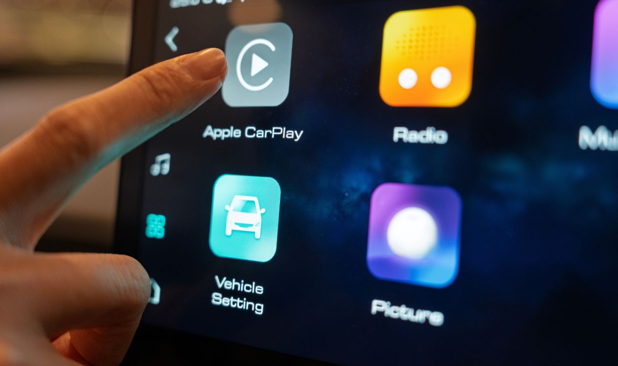 Penang, Malaysia – Aug 9, 2025: A close-up of the infotainment system inside the Haval H6 HEV, showing a user's finger interacting with the Apple CarPlay icon alongside other apps.