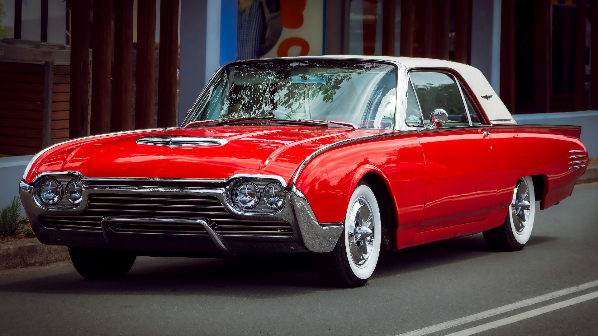 A classic red and white thunderbird car parked on street.