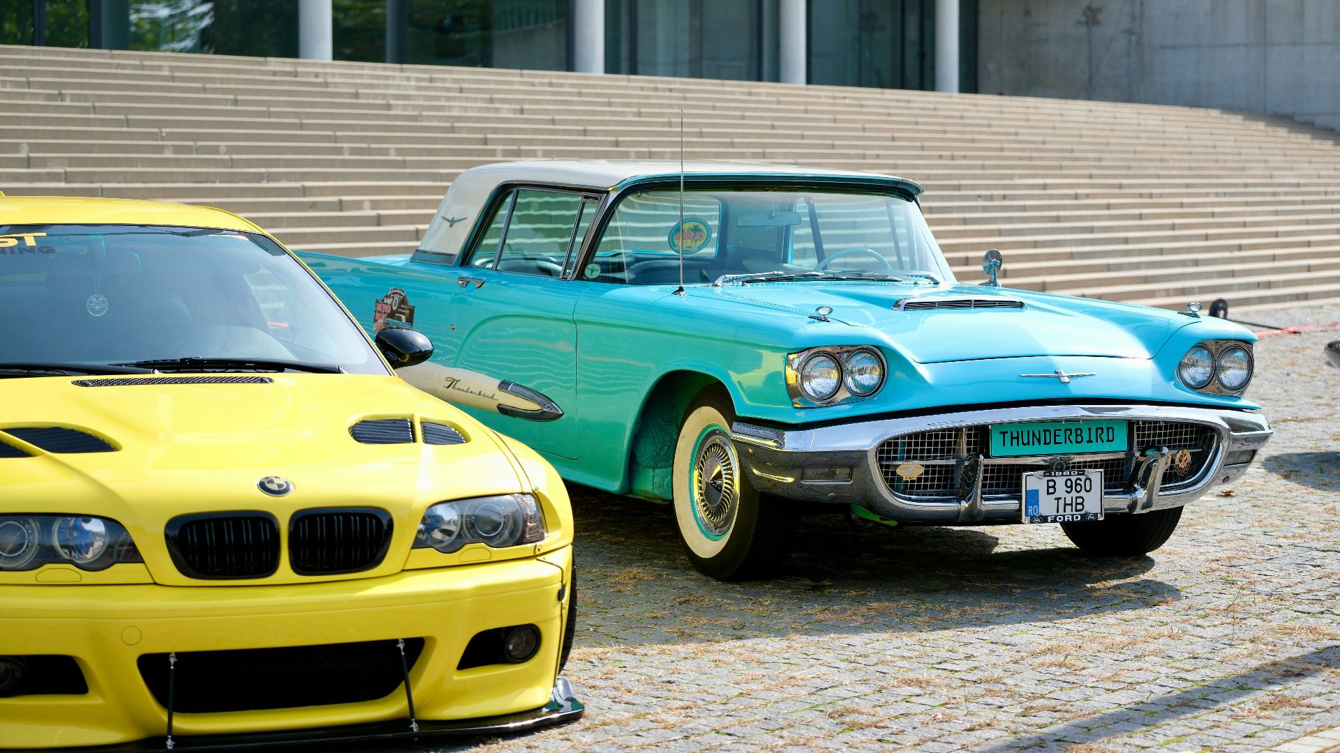 A classic car sits next to a modern sports car.