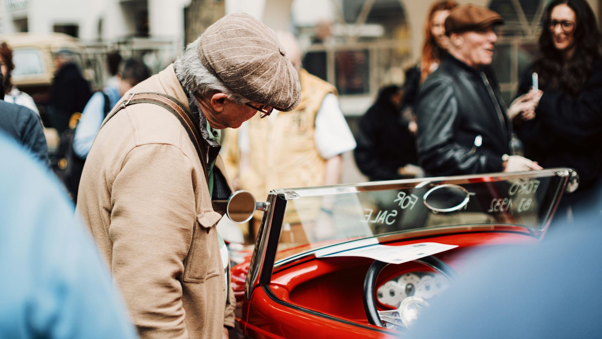 Man in flat cap looking at vintage car
