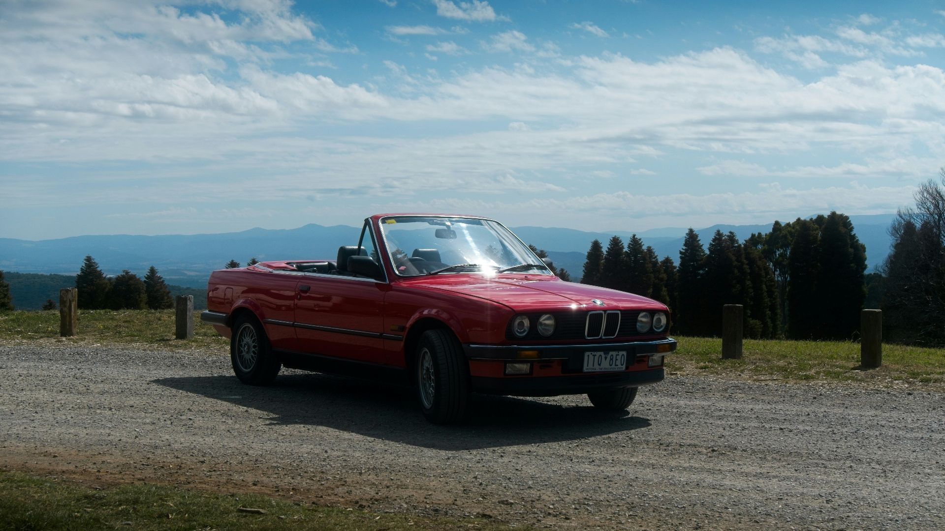 a red convertible car parked on a gravel road