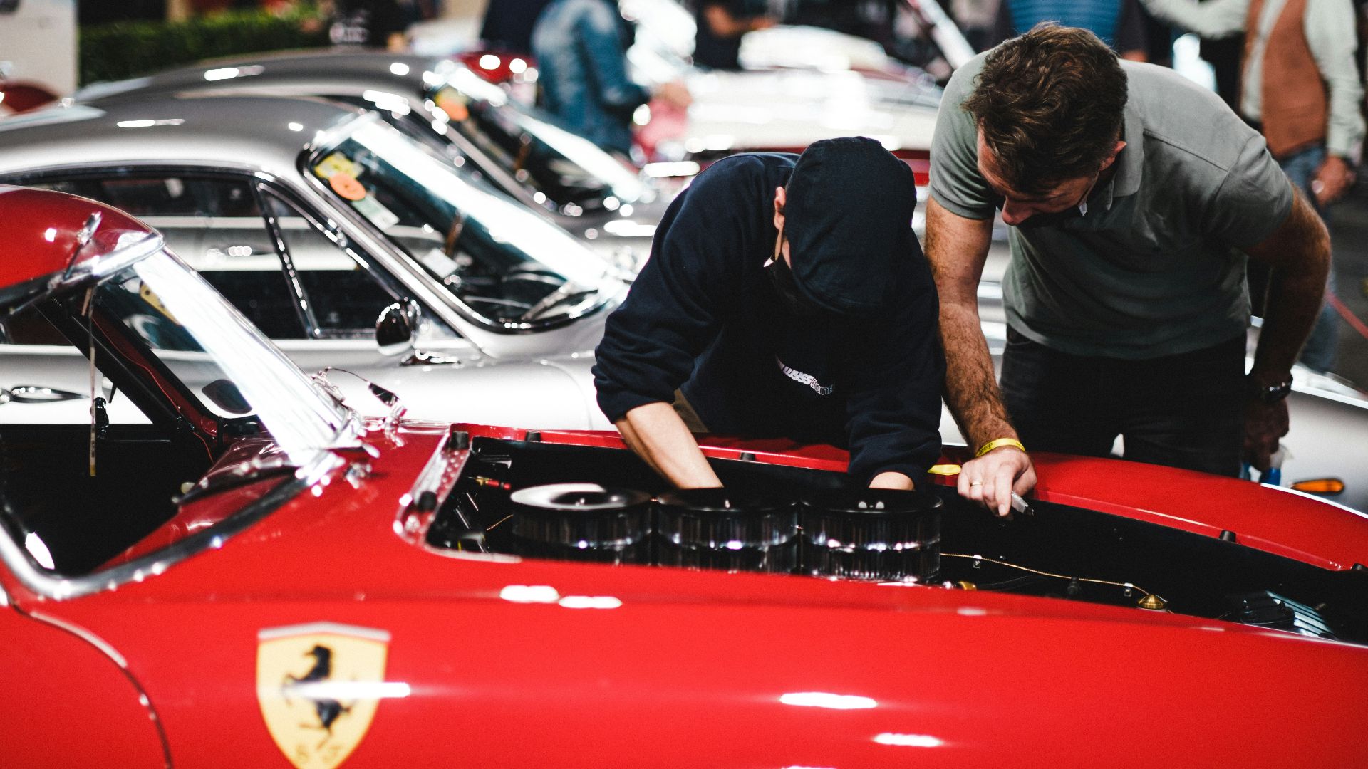 man in black t-shirt and black pants leaning on red car