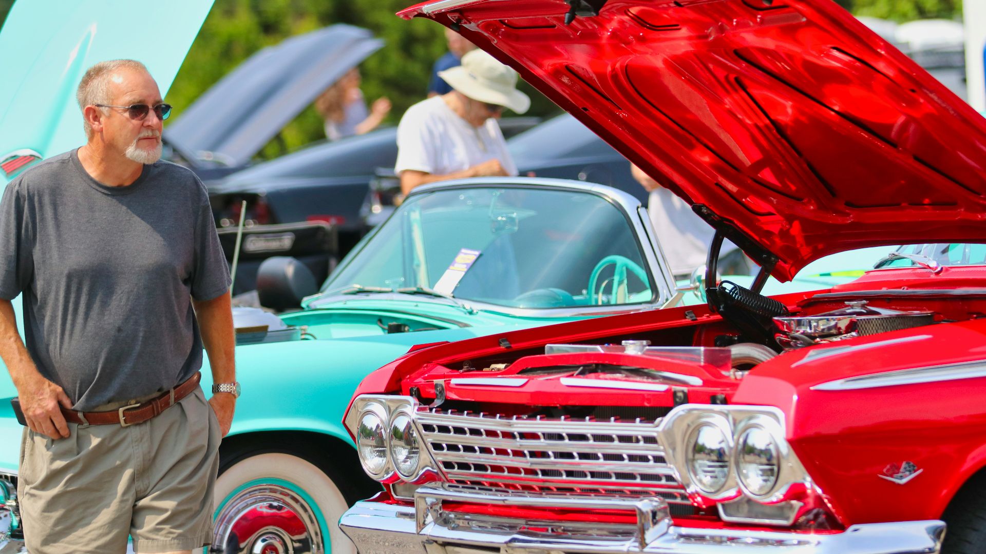 man in black t-shirt standing beside red car during daytime