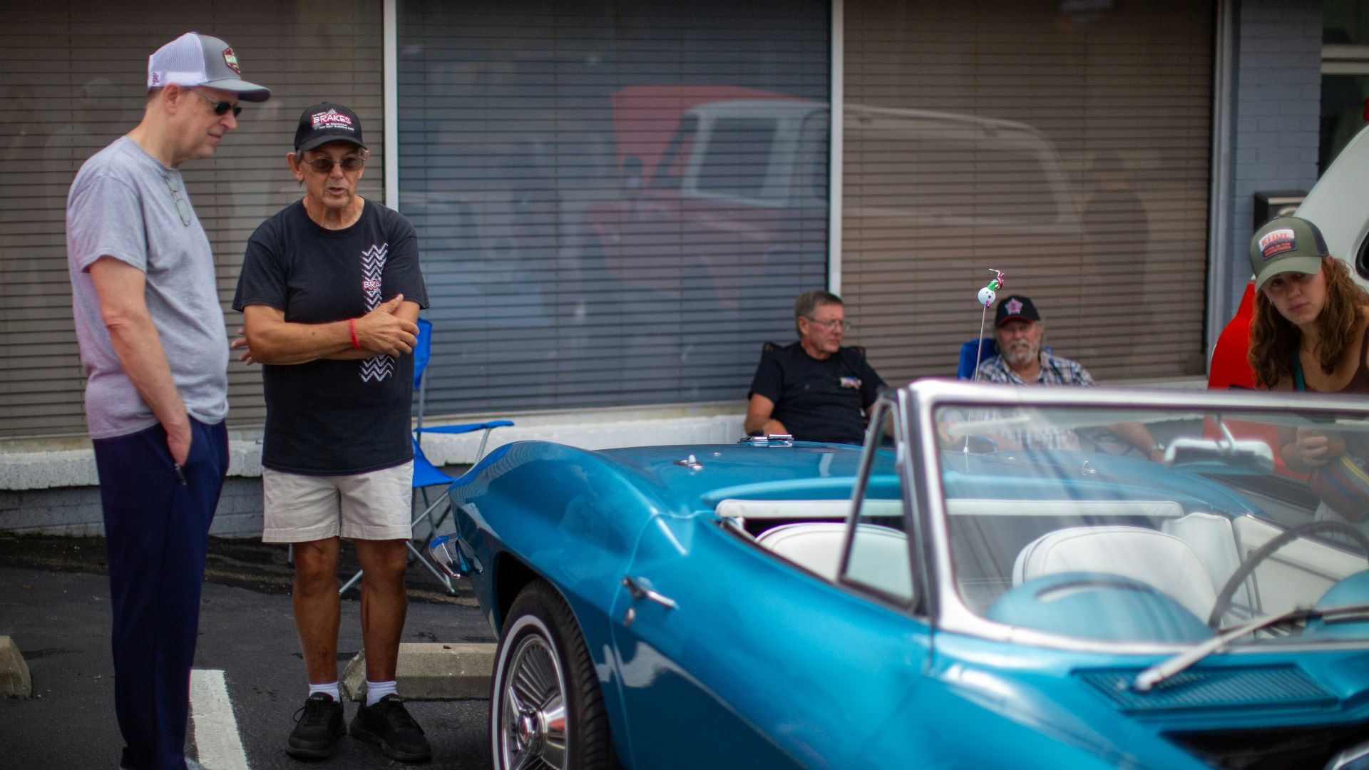 A group of people standing around a blue car