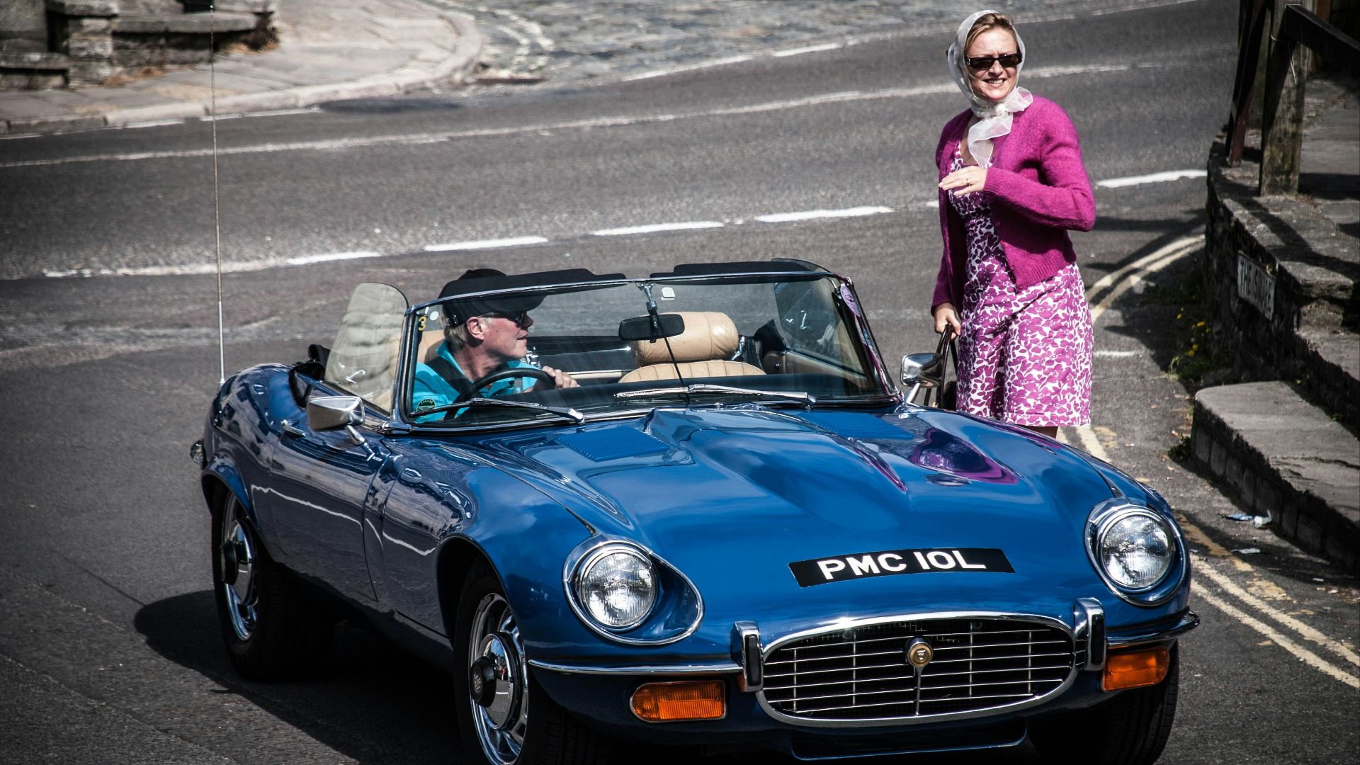 woman in pink long sleeve shirt standing beside blue bmw coupe