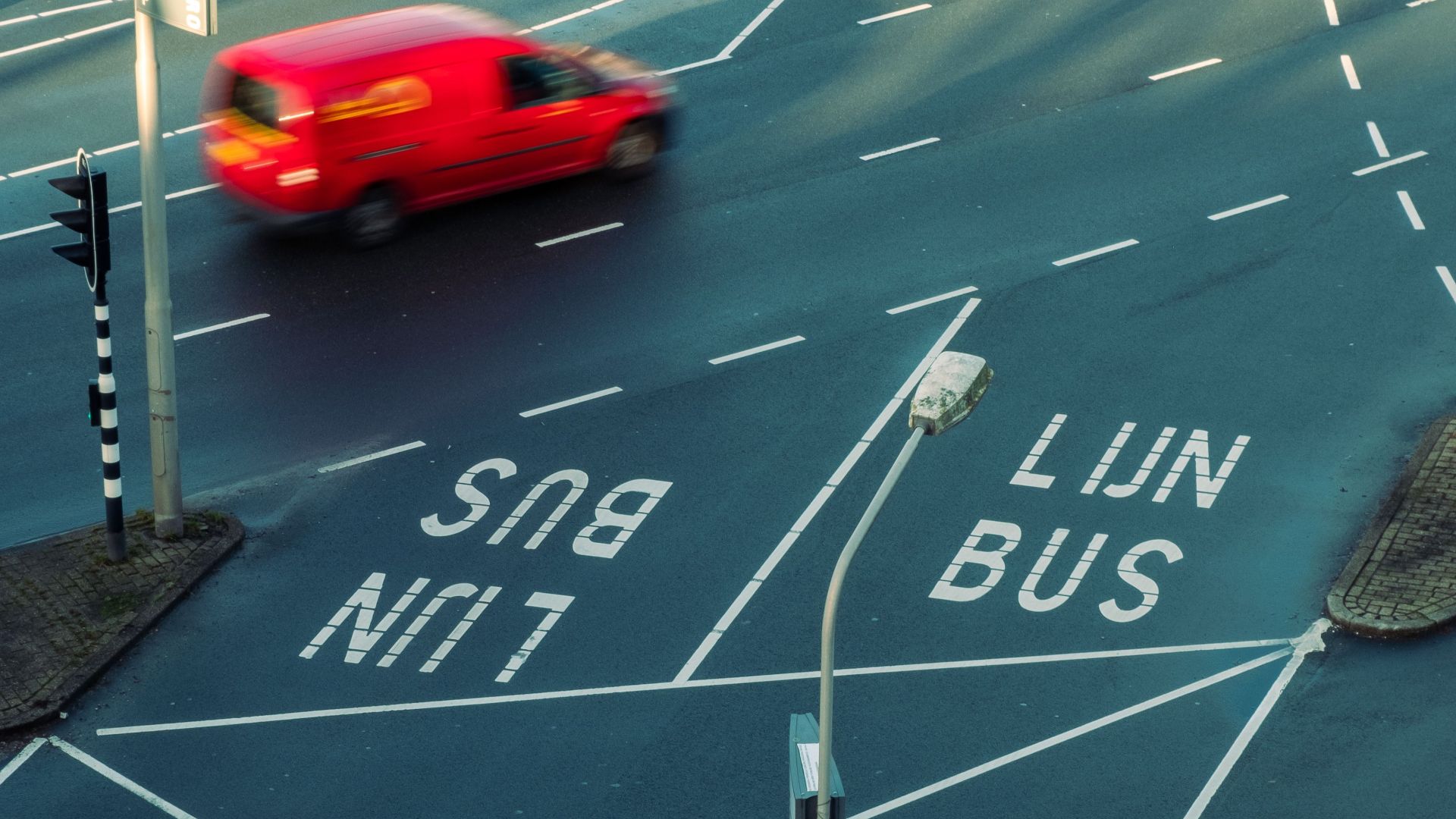 High-angle view of a busy city intersection with bus lanes and moving red car, showcasing urban traffic patterns.